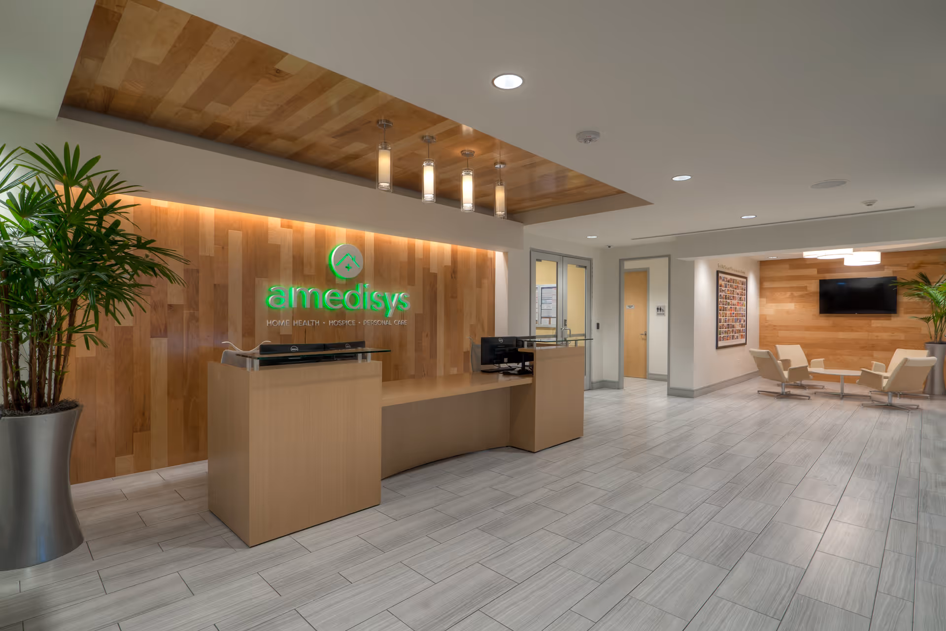 Reception desk with wooden backdrop, illuminated logo, and waiting seating in a modern lobby.
