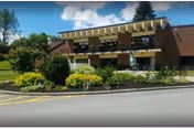 Front exterior of Waterville Residential Care Center with shrubs and a street in front.