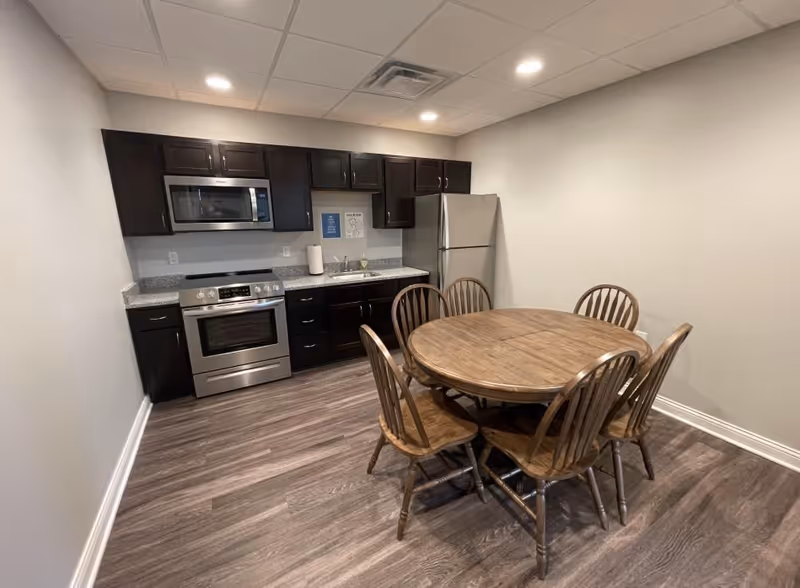Bright communal kitchen and round wooden dining table with six chairs.
