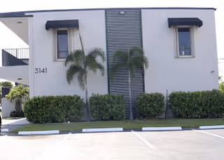 Exterior view of Healing Hands Health Services LLC facility with palm trees and a parking lot.