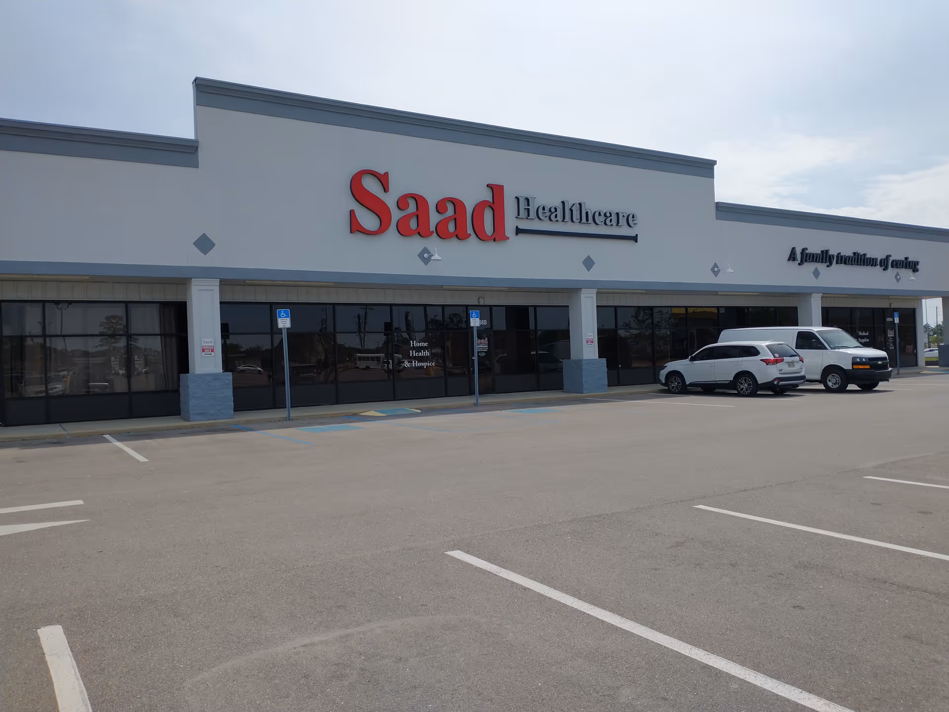 Exterior view of Saad Healthcare building with parking lot and two cars.