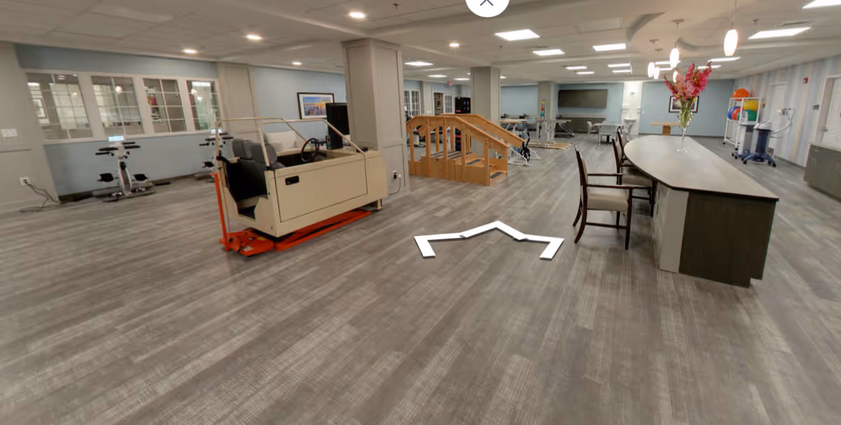 Spacious indoor common area with exercise equipment, stairs, and a long reception counter.