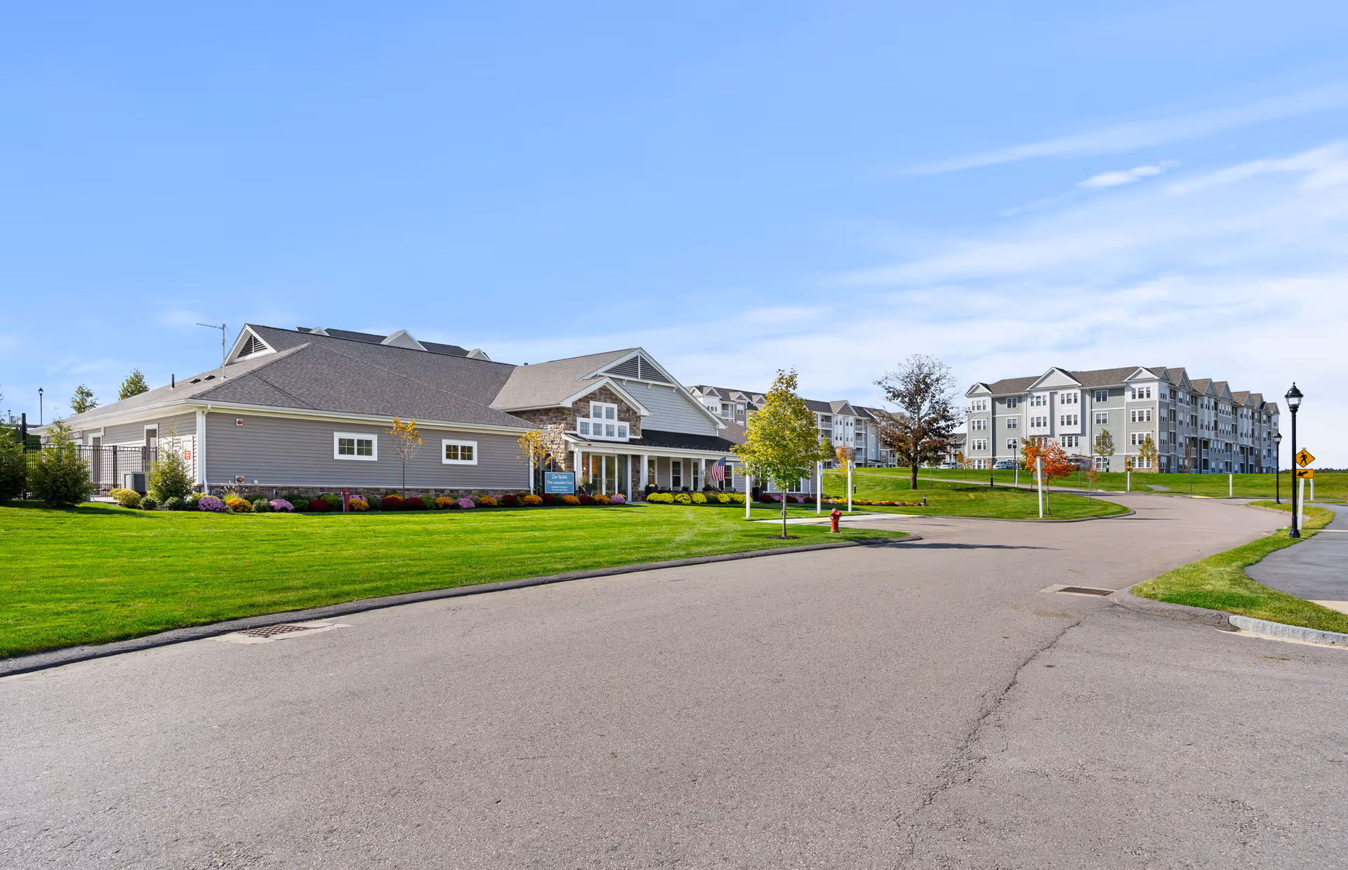 Exterior view of Chauncy Lake senior living campus with manicured lawns and a curved road.