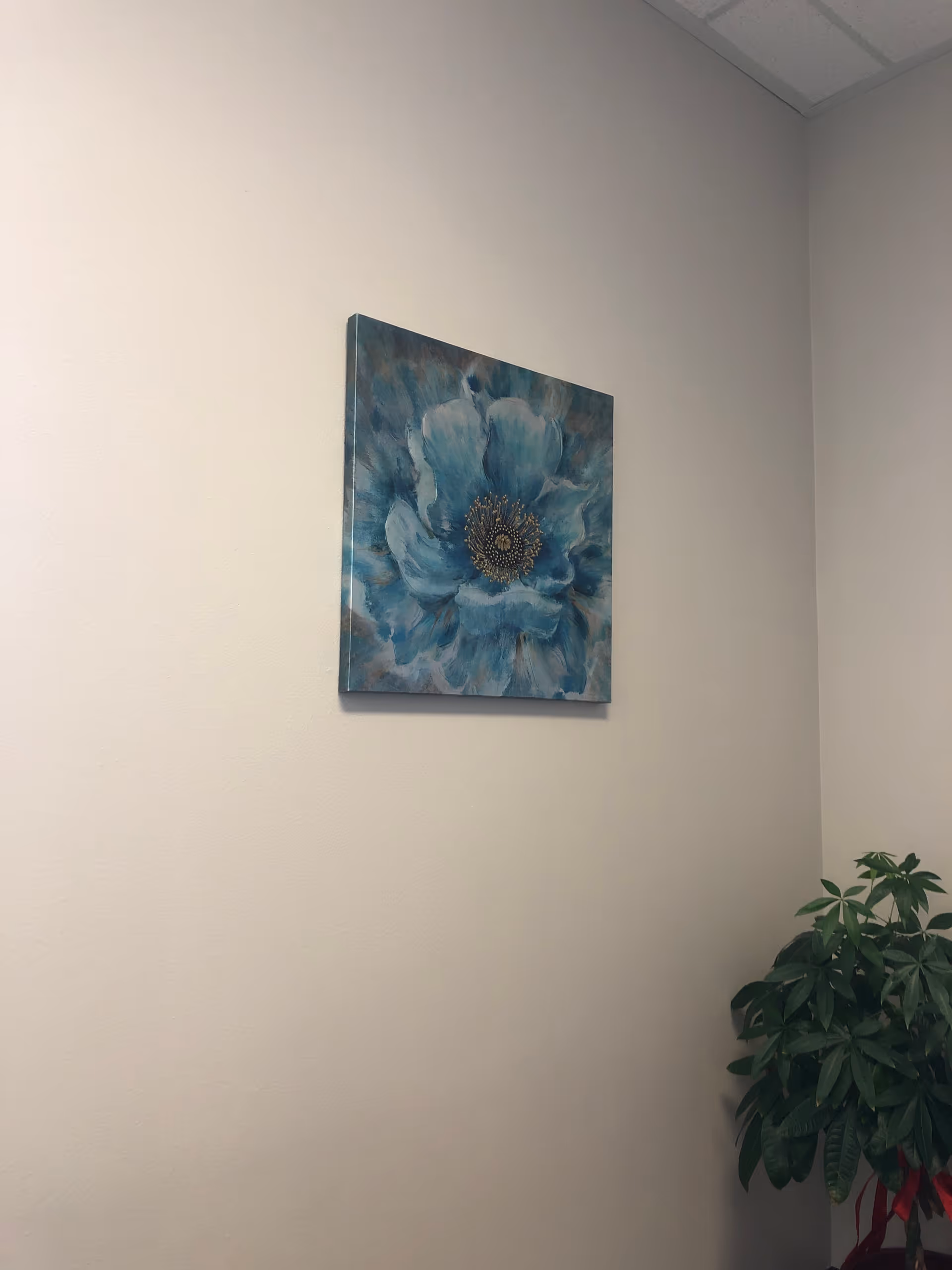 An interior wall features blue flower artwork with a potted plant in the corner.
