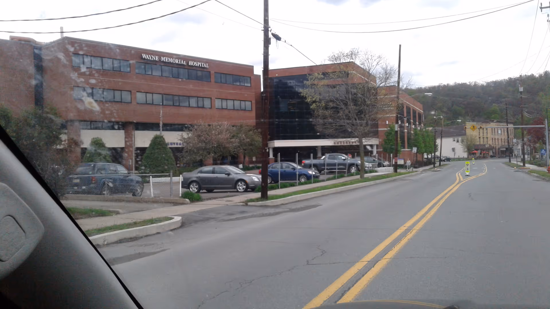 Exterior view of Wayne Memorial Hospital building along a street with parked cars and power lines.