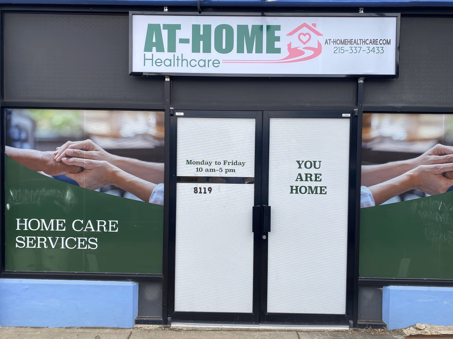 Front of At-Home Healthcare building with double doors and YOU ARE HOME signage.