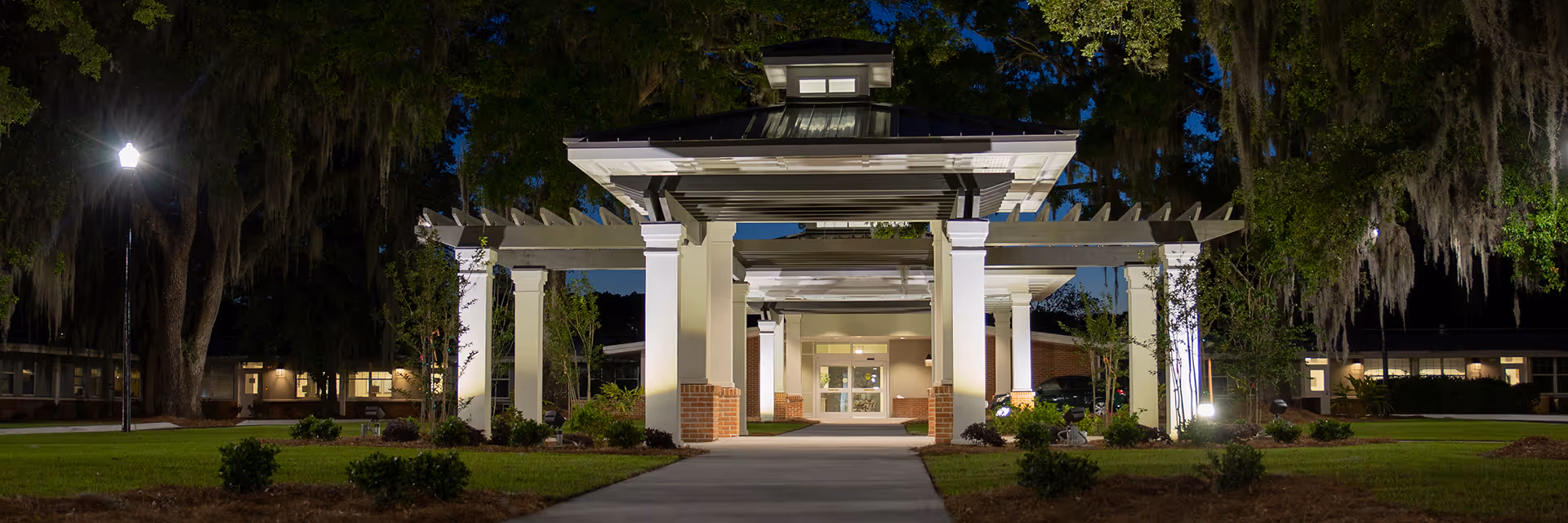 Night view of Riverview Health and Rehab Center Savannah entrance with illuminated walkway.