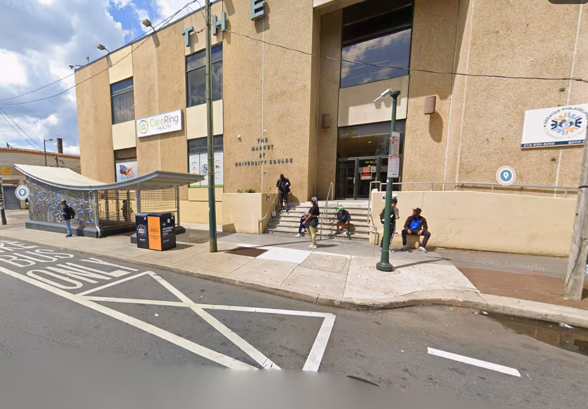Exterior view of the facility entrance with several people seated on steps outside.