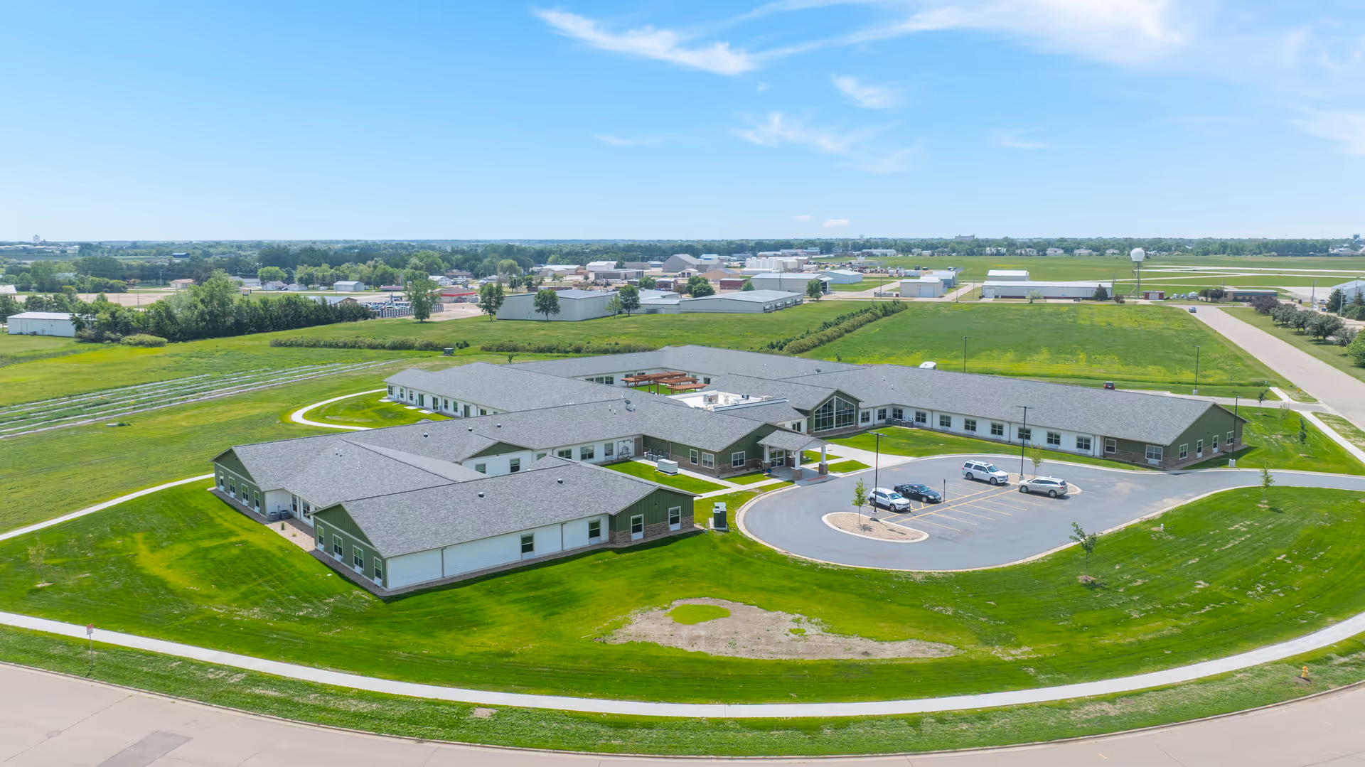 Aerial view of a multi-wing senior living campus with green lawns and parking.