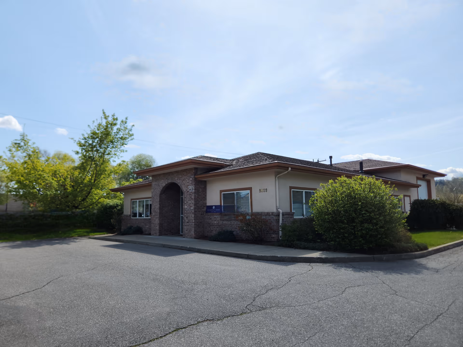 Exterior view of a single-story senior living facility with brick entrance and landscaped lawn.