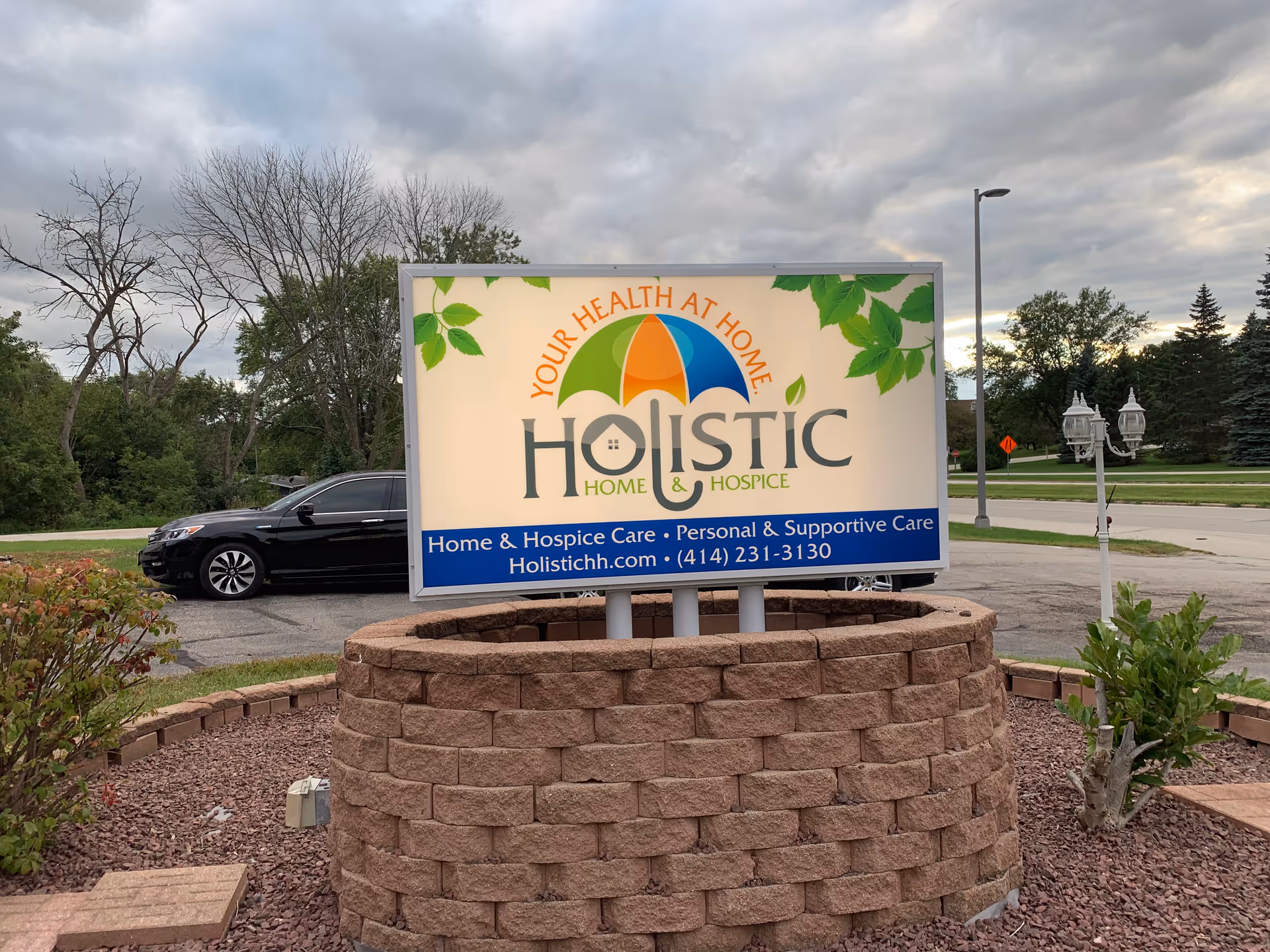 Outdoor sign for Holistic Home & Hospice Care on a brick planter.