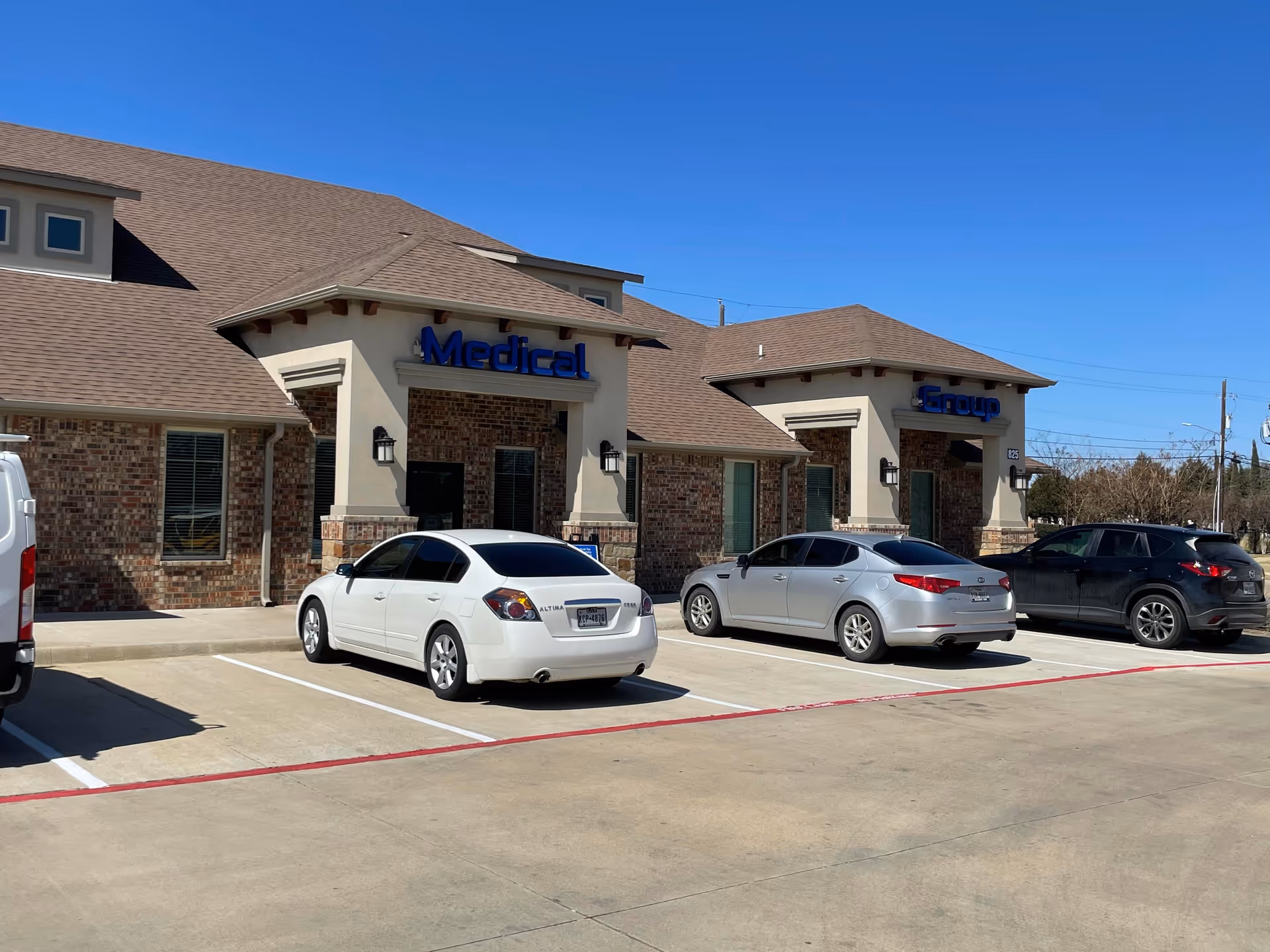 Exterior view of a brick medical group building with parked cars.