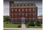 Red brick Loretto Home senior living building, viewed from lawn with front entrance.