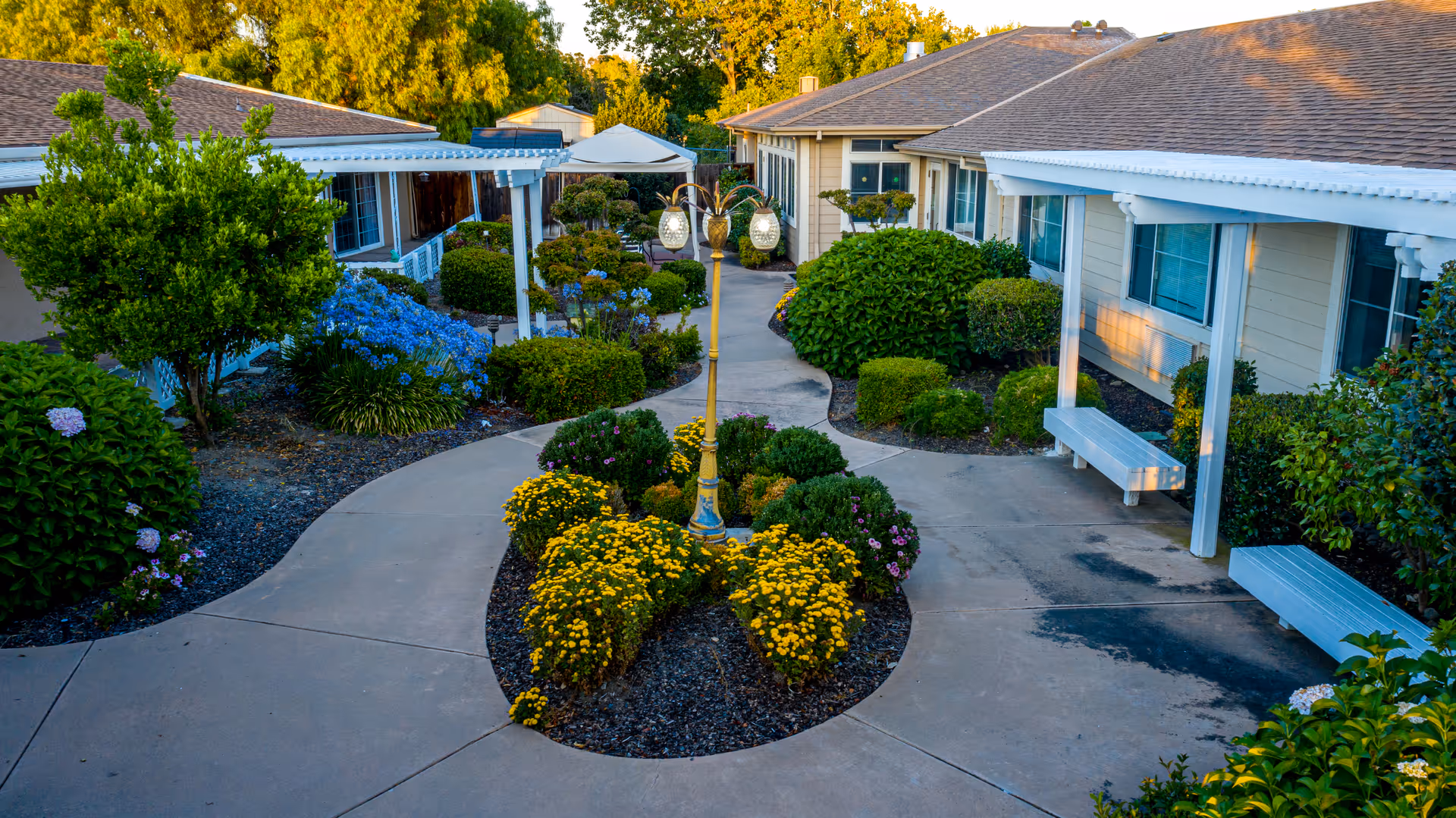 Sunny courtyard path between Avondale Villa Post-Acute buildings with manicured landscaping.