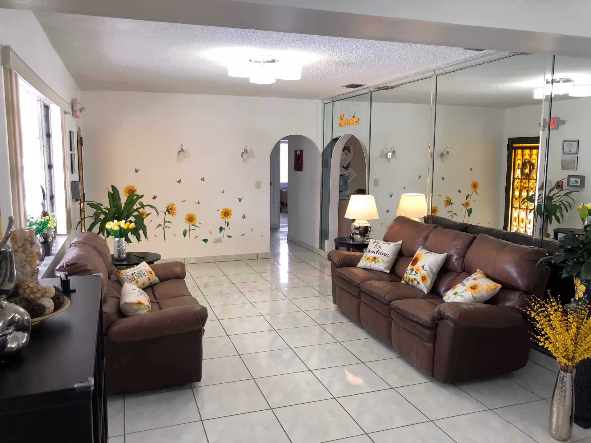 Bright Sunshine Home ALF lounge with brown leather sofas and sunflower decor.
