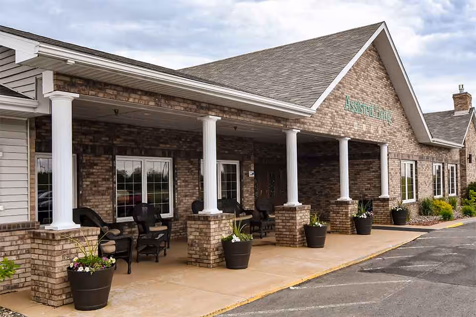 Exterior view of a brick assisted living facility with a covered porch and seating