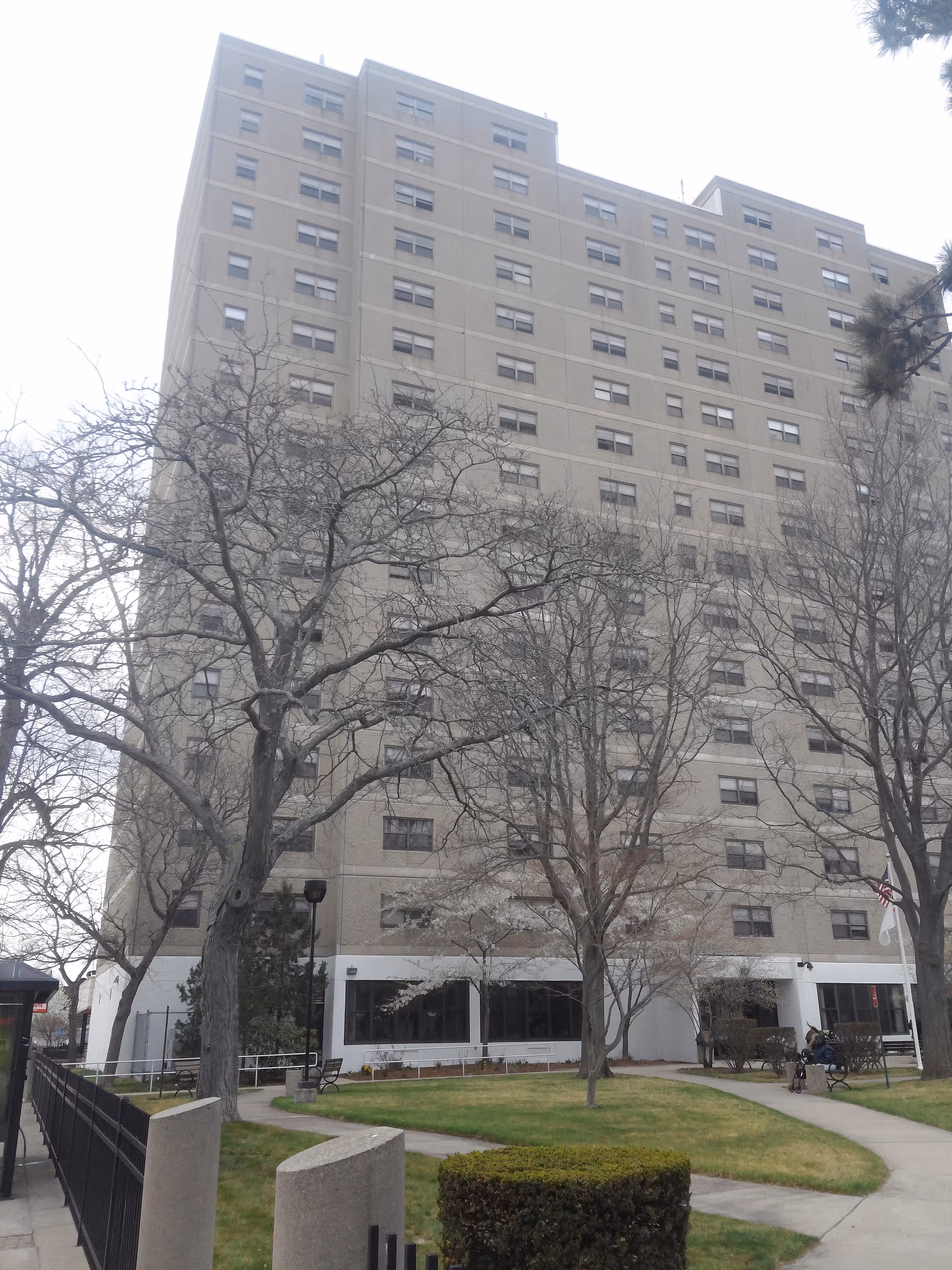 Exterior view of Carroll Tower, a tall senior living building, with leafless trees and lawn.