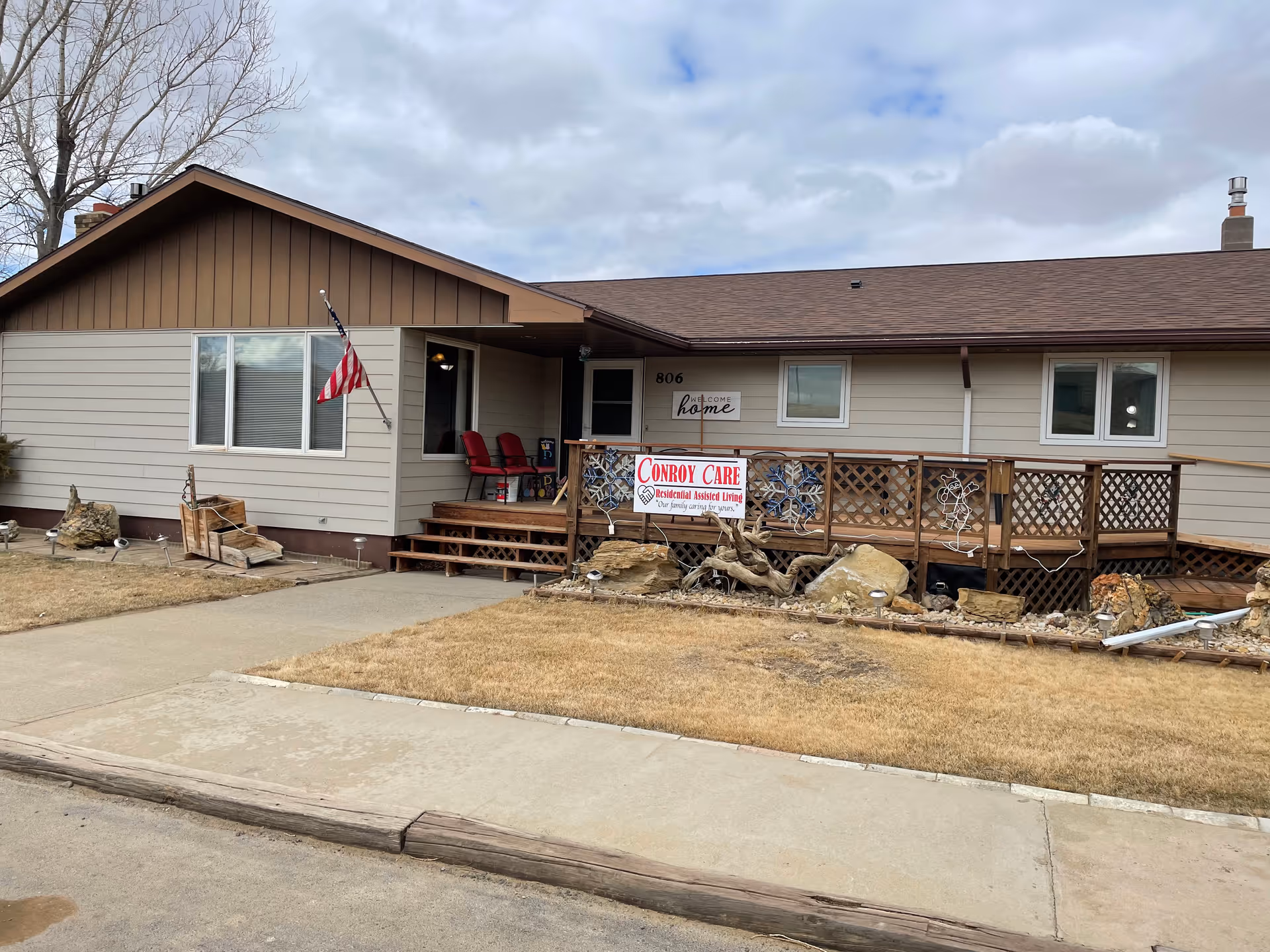 Single-story building with a wooden front deck, chairs, and a Conroy Care sign.