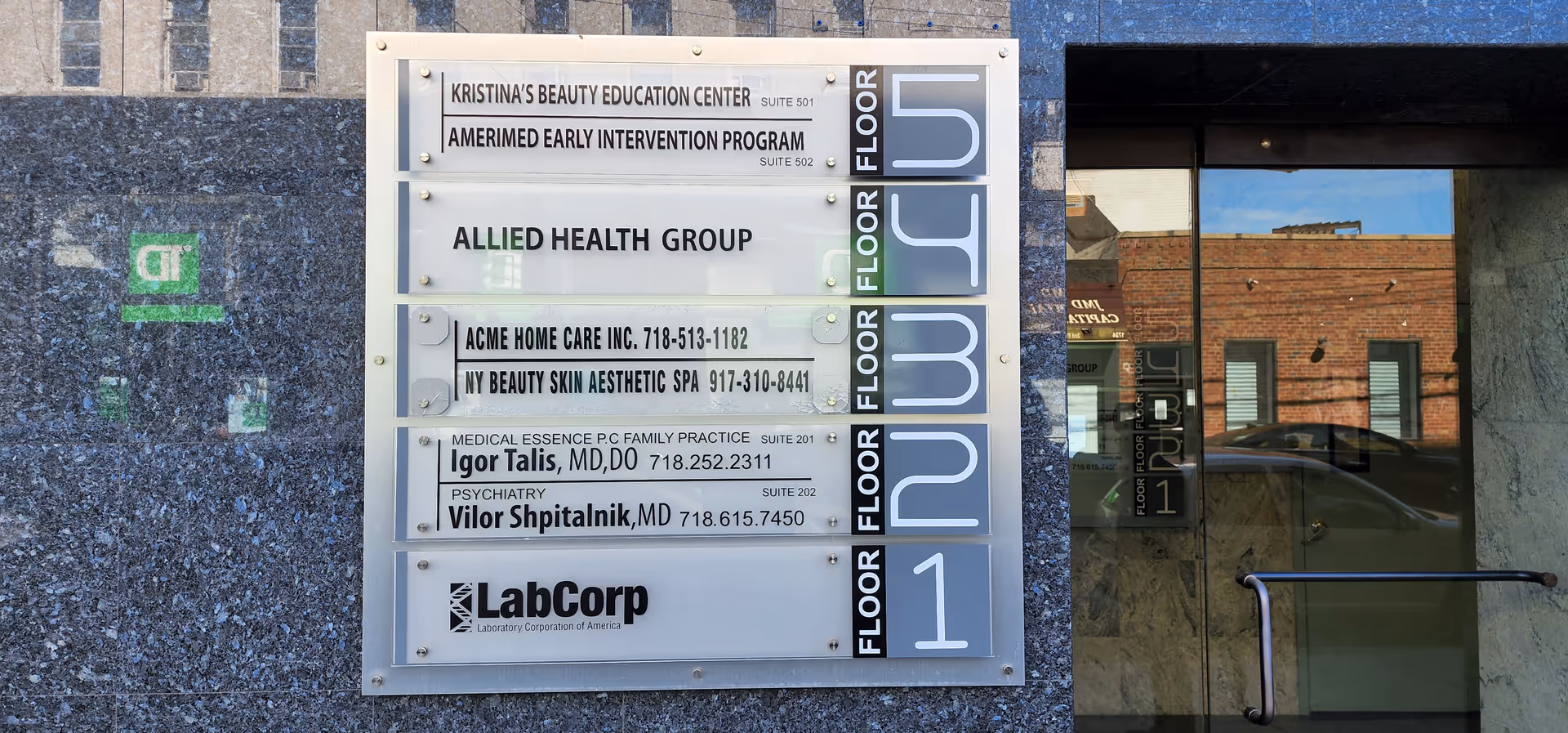 Exterior building entrance with directory sign listing tenants, including ACME Home Care