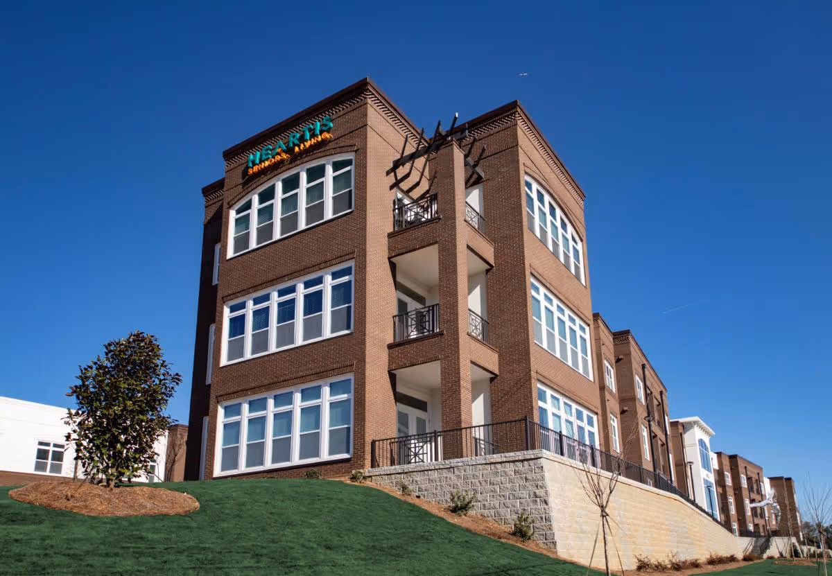 Exterior view of Heartis Suwanee Senior Living building with balconies and landscaped lawn.