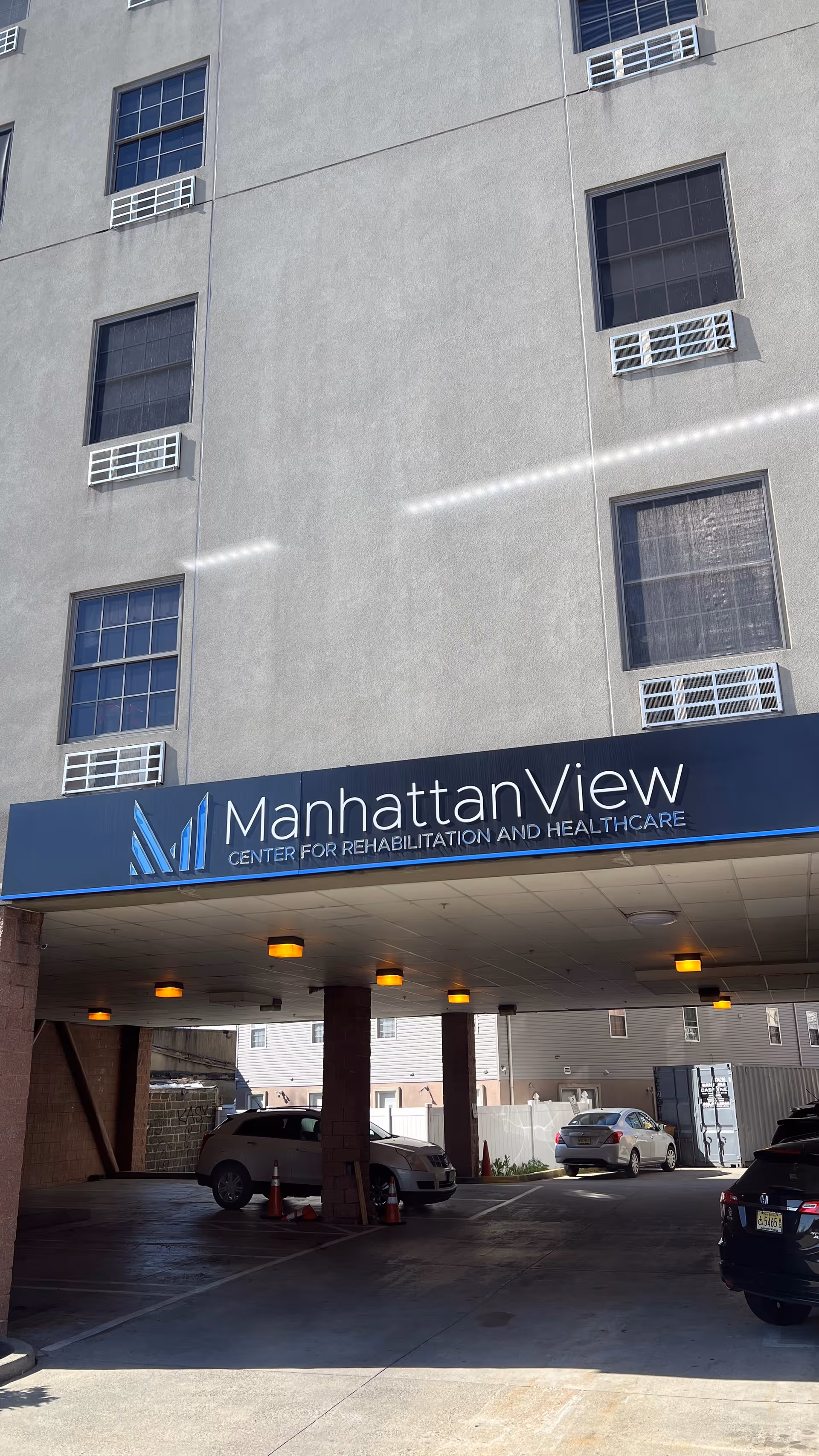 Tall grey building with ManhattanView sign and a covered driveway entrance.