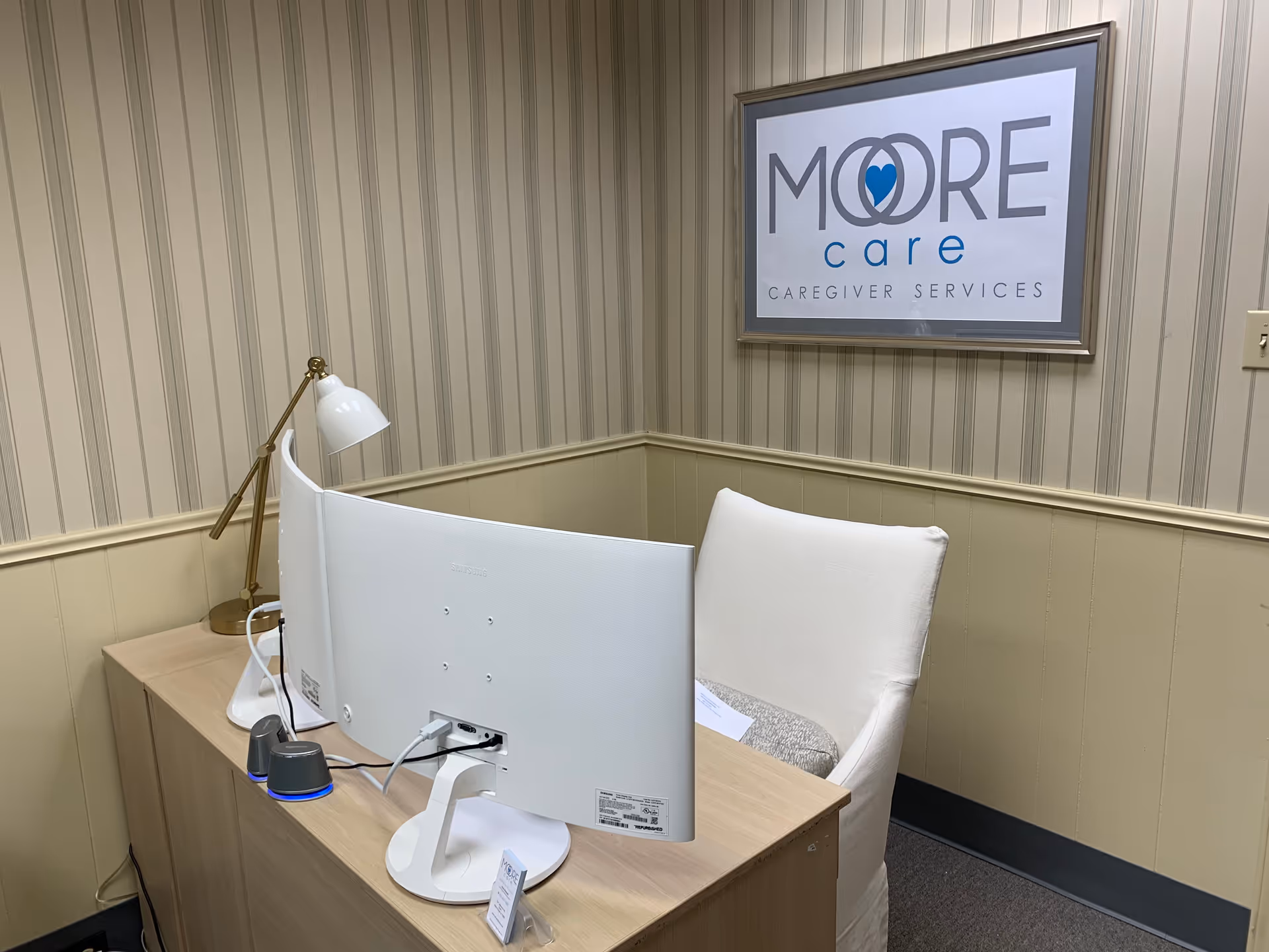 Reception desk with computer and Moore Care logo on striped beige walls