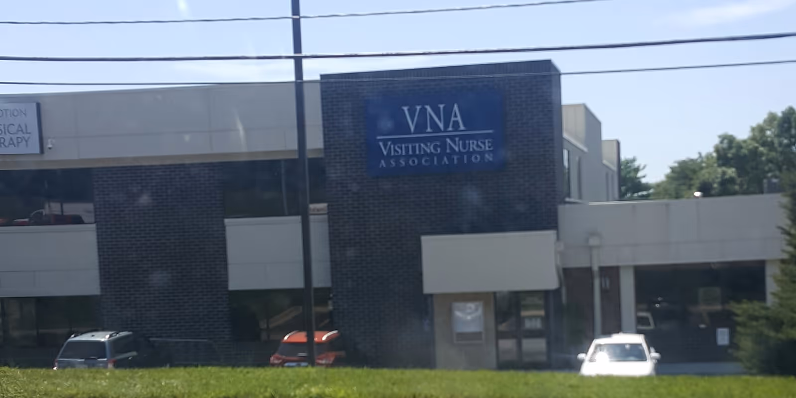 Exterior view of a VNA building with blue sign and parked cars.