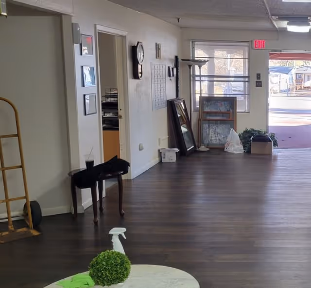 Long indoor hallway of a senior living facility with scattered furniture and an exit door.