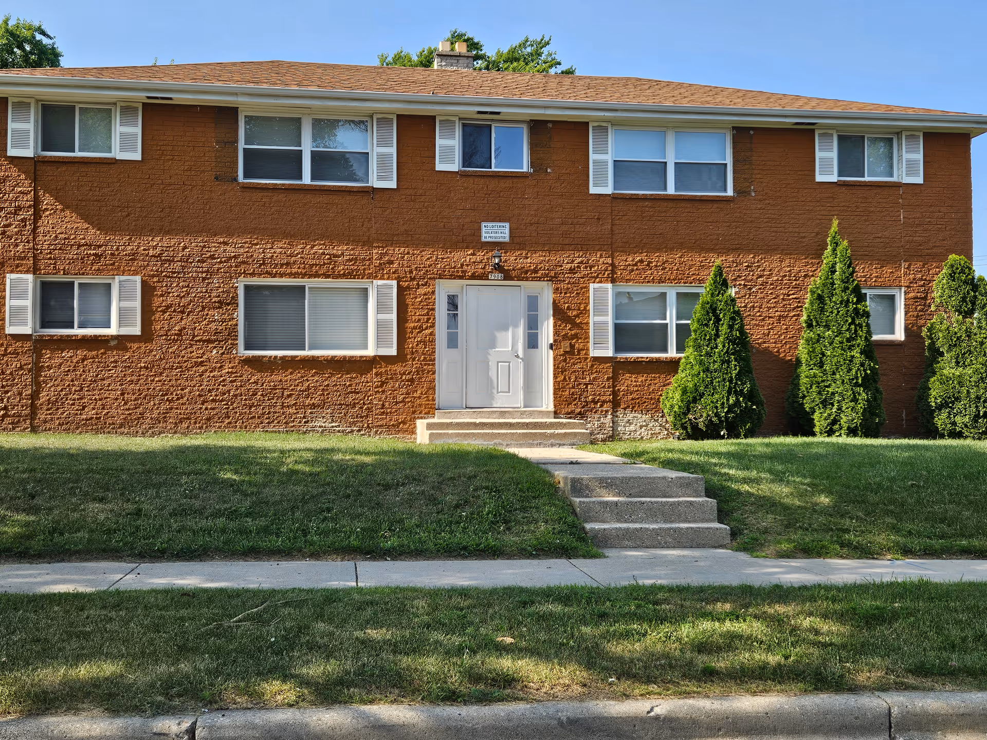 Two-story brick senior living facility with central entrance and front lawn.