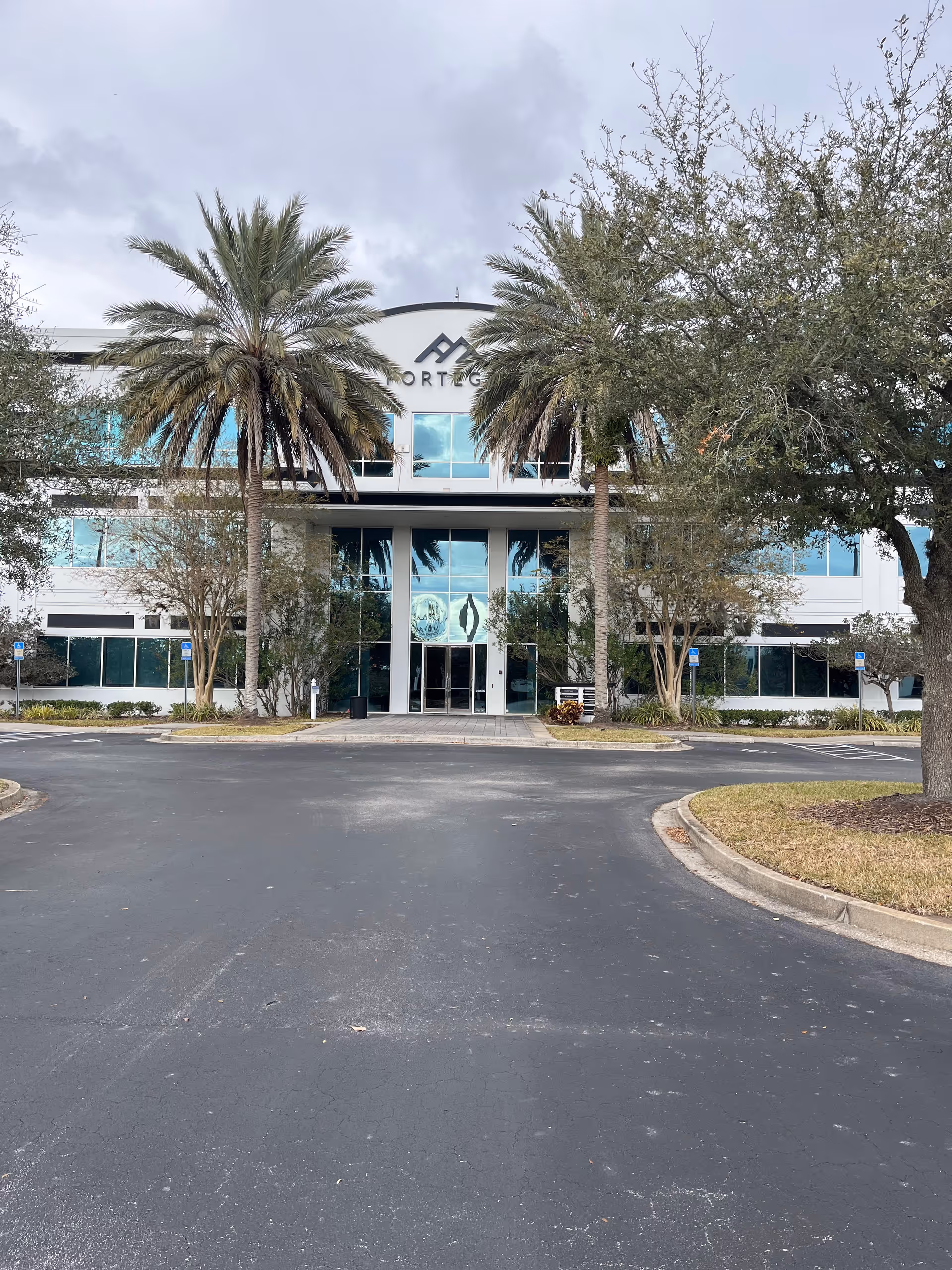Exterior view of a modern senior living facility entrance framed by palm trees.