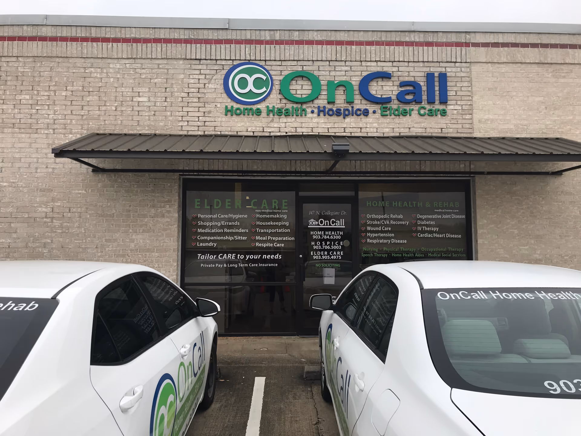 Exterior view of OnCall building storefront with parked white cars in front.