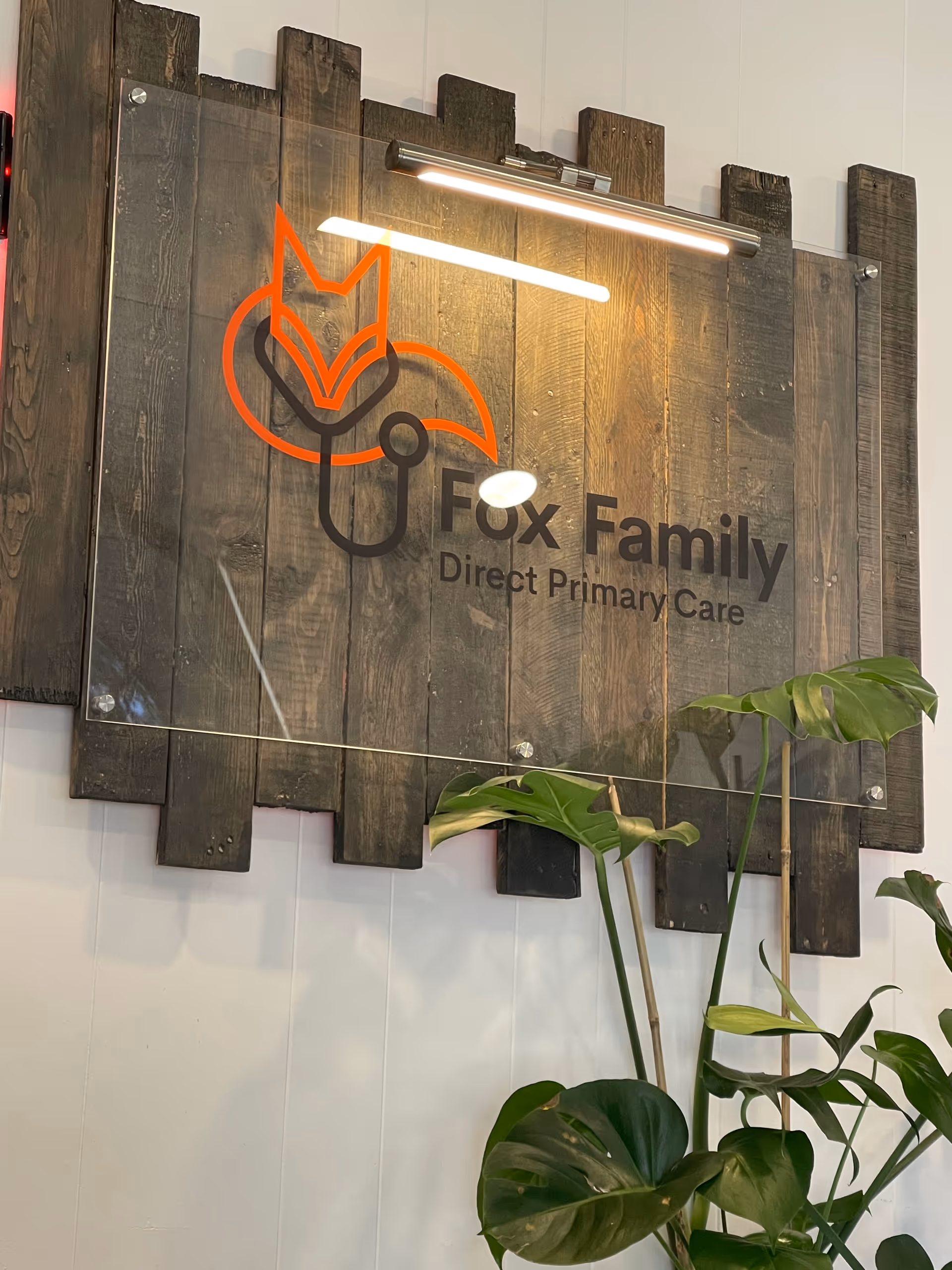 Wooden wall sign displaying Fox Family Direct Primary Care logo with orange fox emblem.
