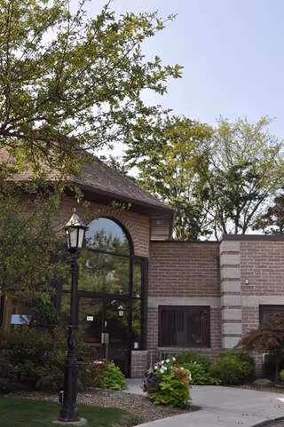 Exterior view of a brick nursing home entrance with landscaping and a decorative lamppost