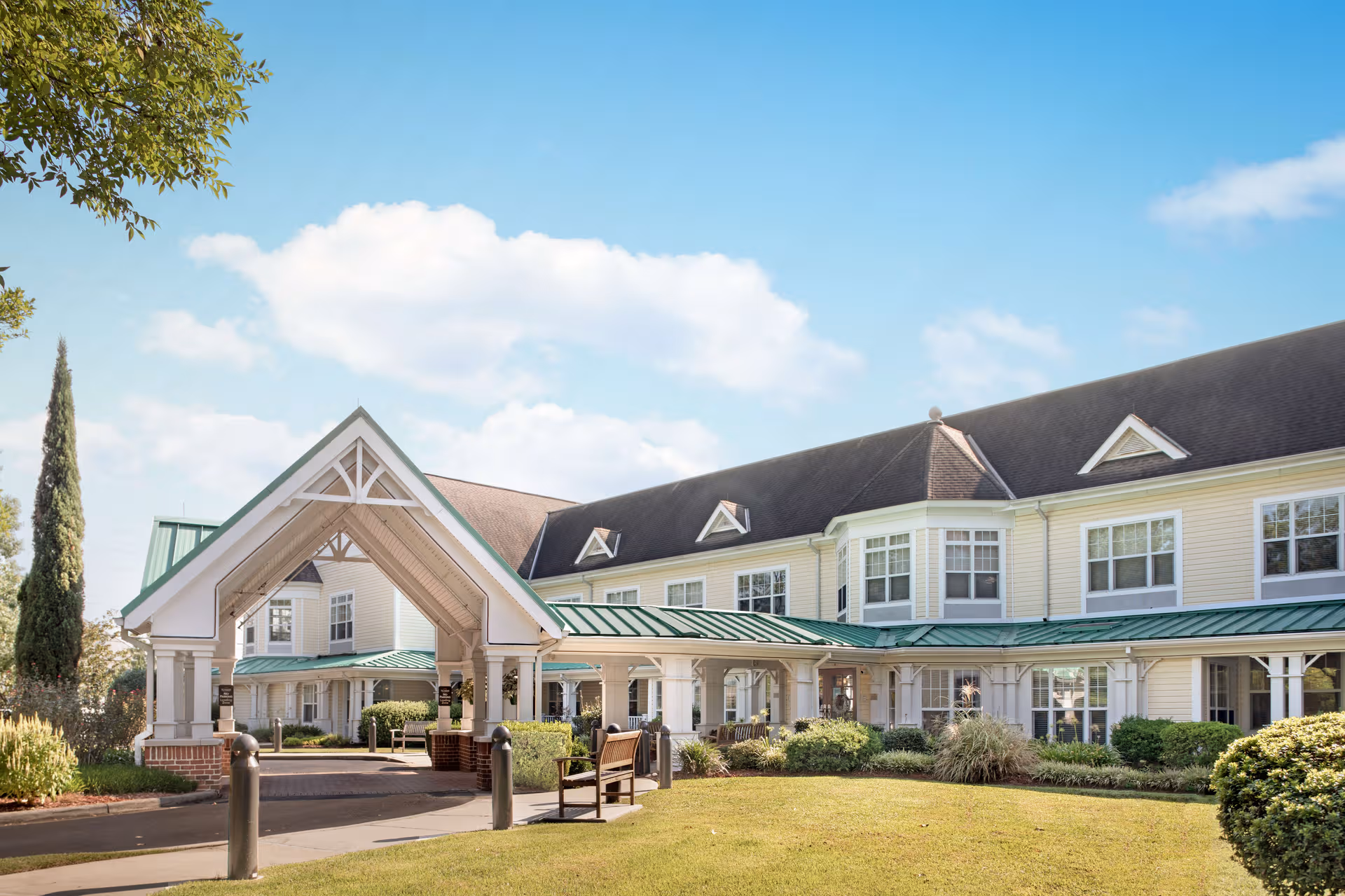 Sunny exterior view of Sunrise of Baton Rouge, showing the entrance and landscaped front yard.