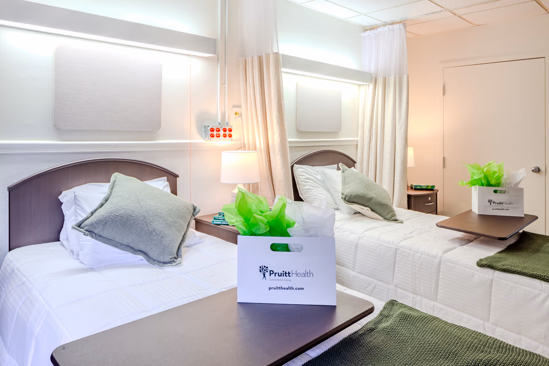 Two twin beds with white linens and green pillows in a shared hospital-style bedroom.