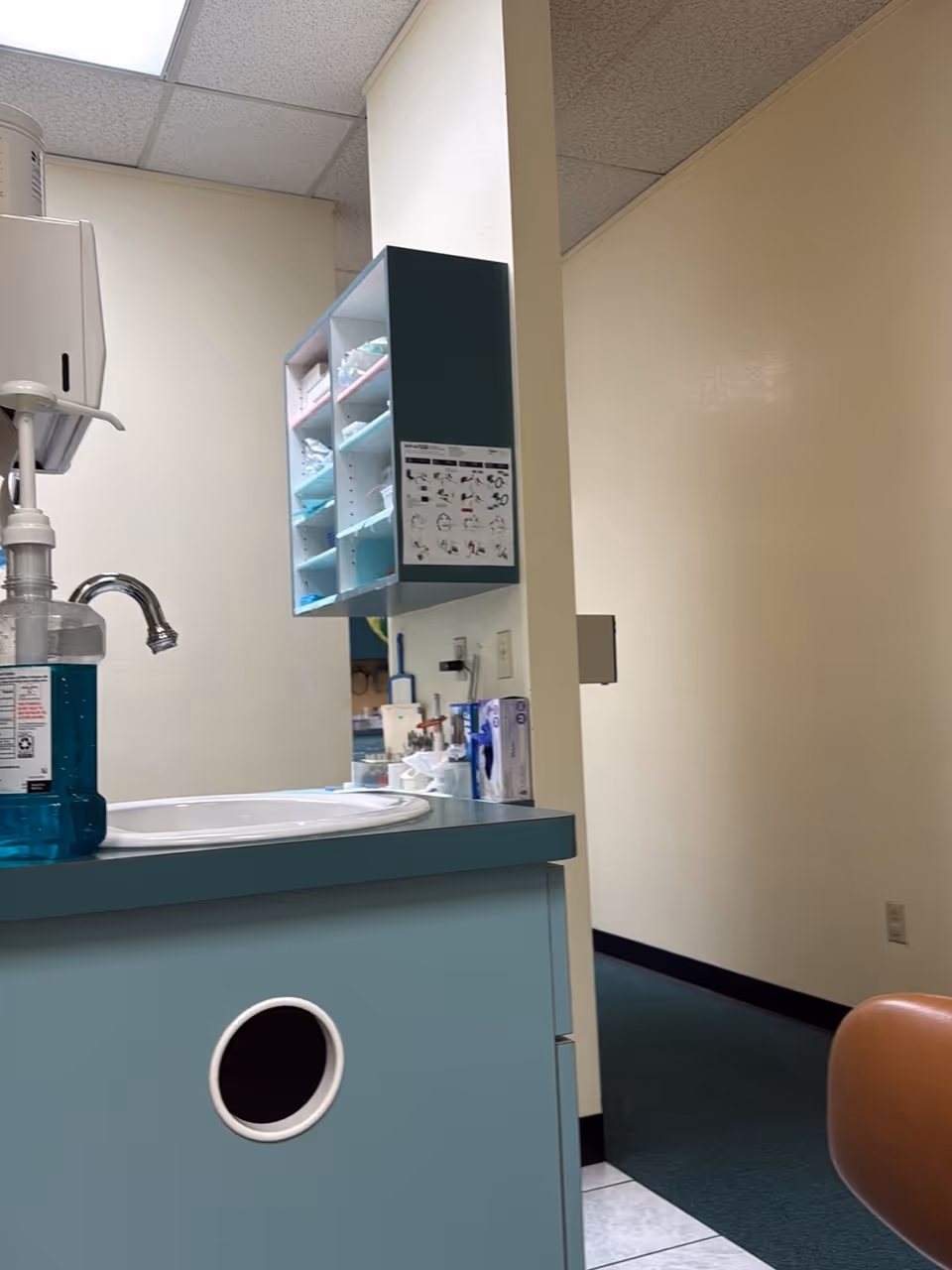 Clinical sink area with teal cabinetry and scattered medical supplies along a wall
