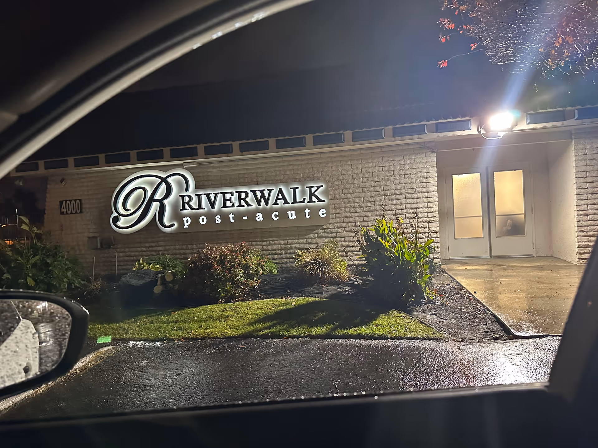 Night exterior of Riverwalk Post Acute building with illuminated sign and entrance.