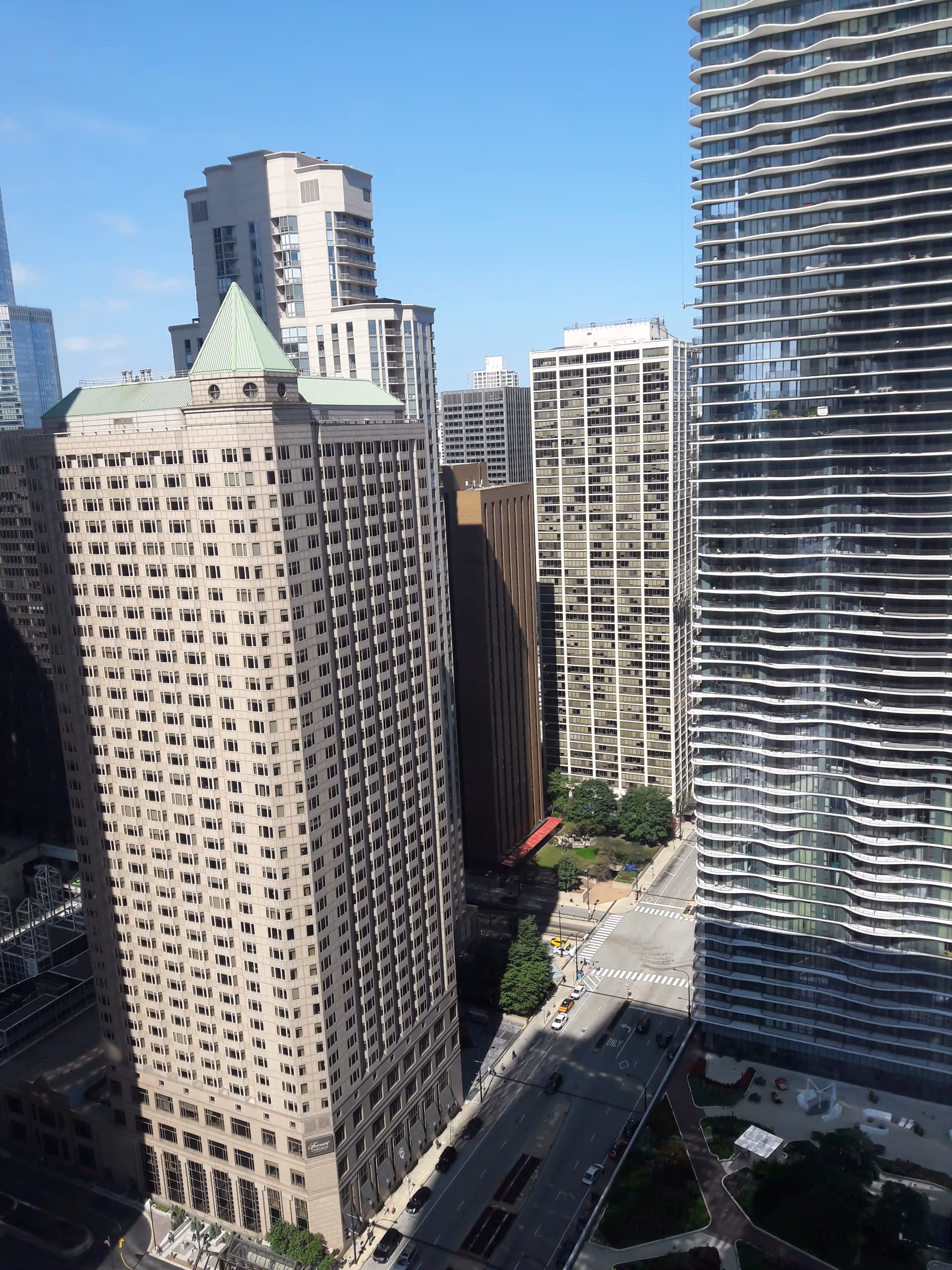 A cityscape of tall modern office buildings along a street under a clear blue sky.