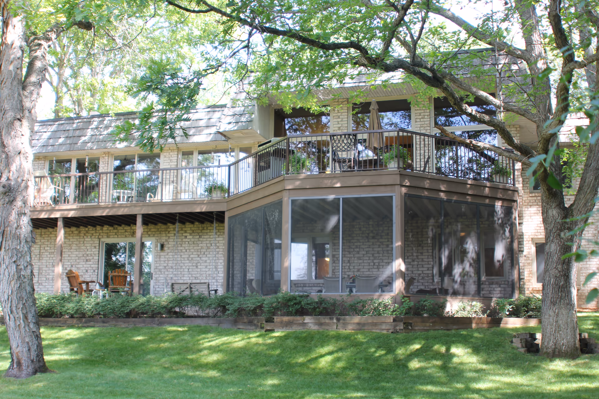 Brick senior living facility with a screened porch, balcony, and surrounding trees.