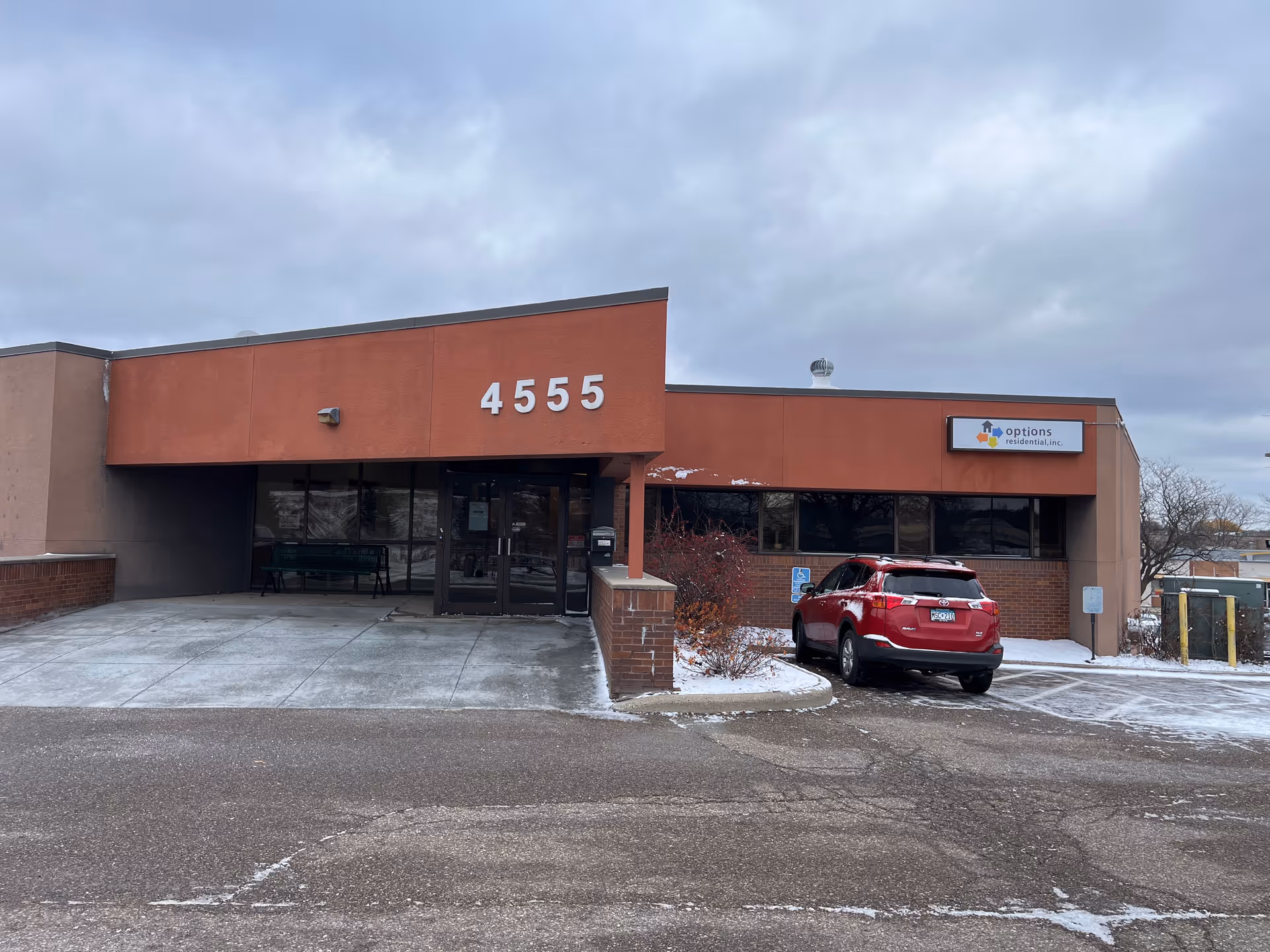 Exterior view of Options Cedar facility with 4555 address, red brick, and a parked car.
