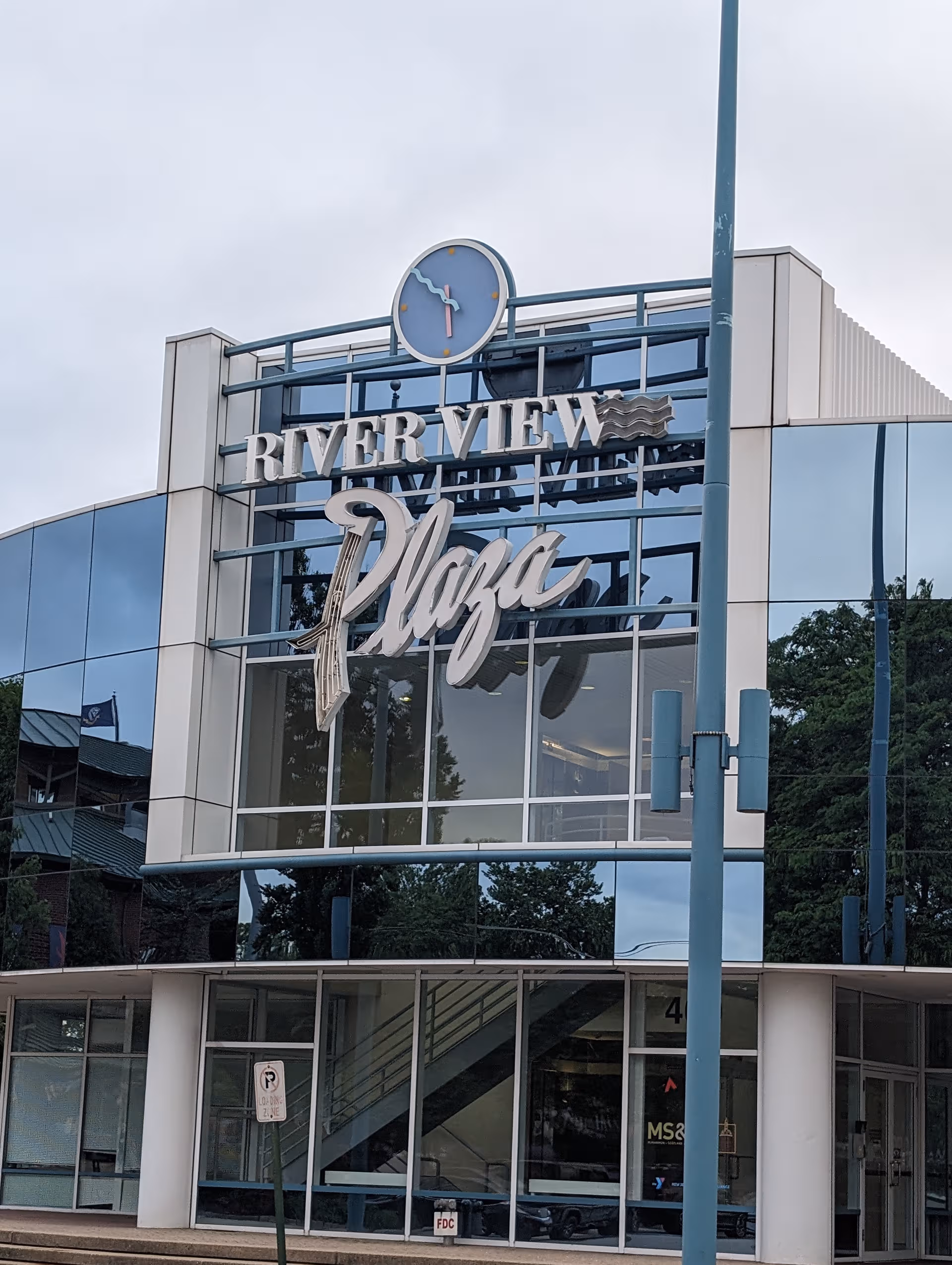 Glass-front building facade with River View Plaza sign and round clock above