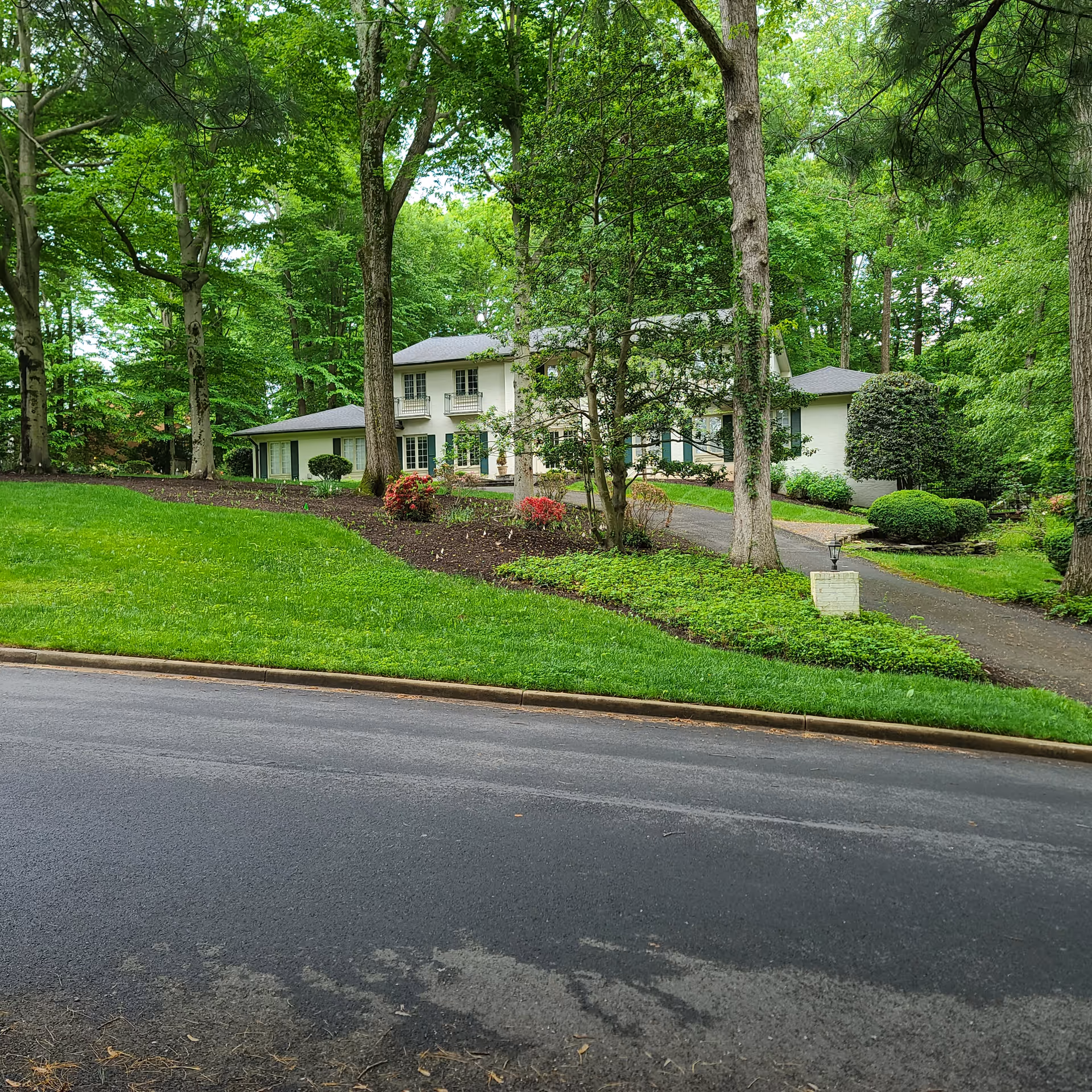 Front view of a white two-story senior living building surrounded by trees and a curved driveway.