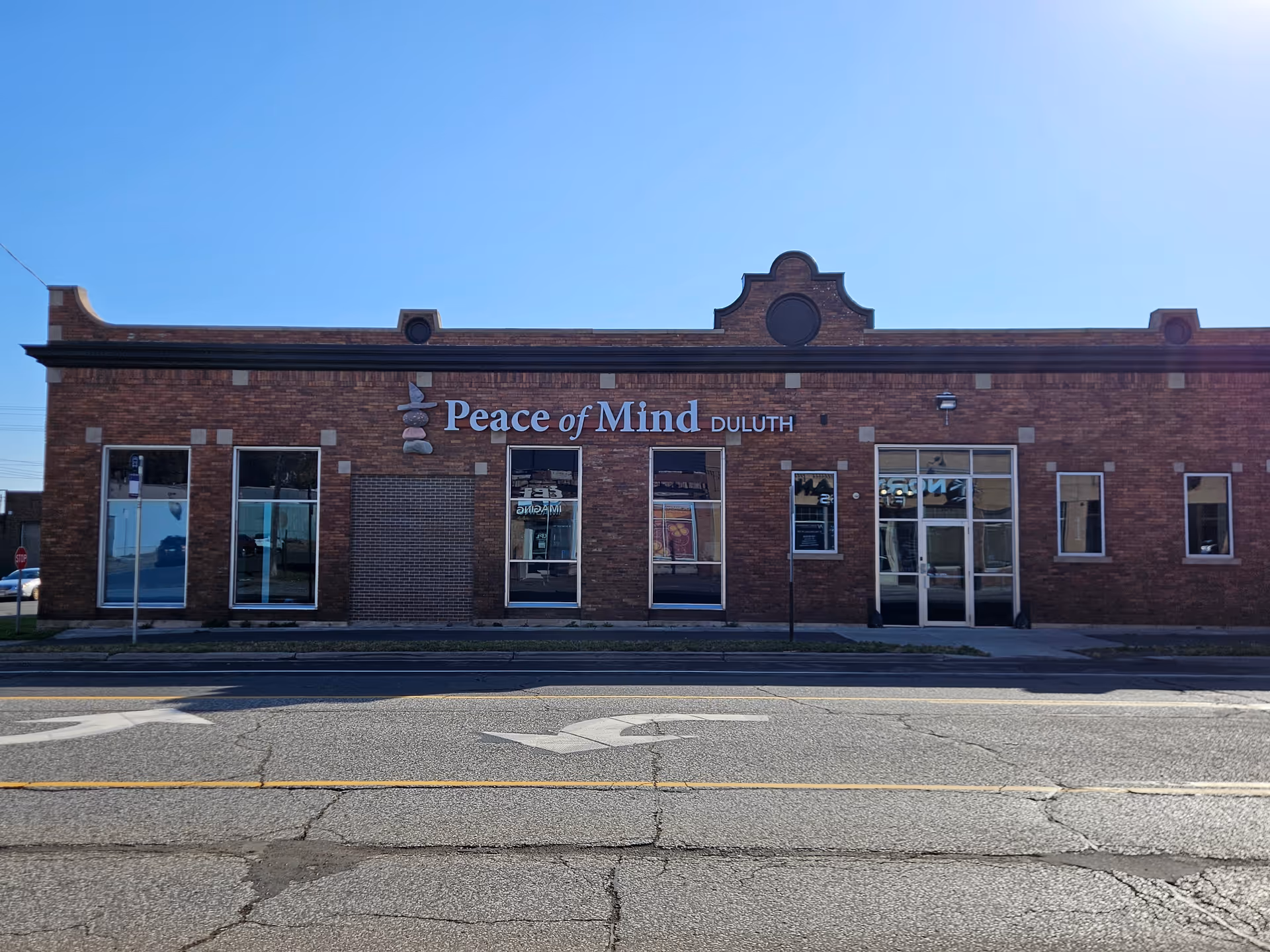Brick storefront displaying Peace of Mind Duluth sign along a sunny street.