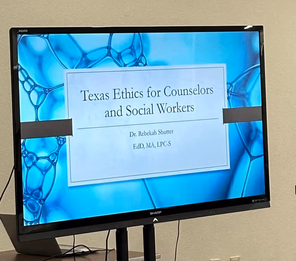 Monitor displays presentation slide titled Texas Ethics for Counselors and Social Workers.