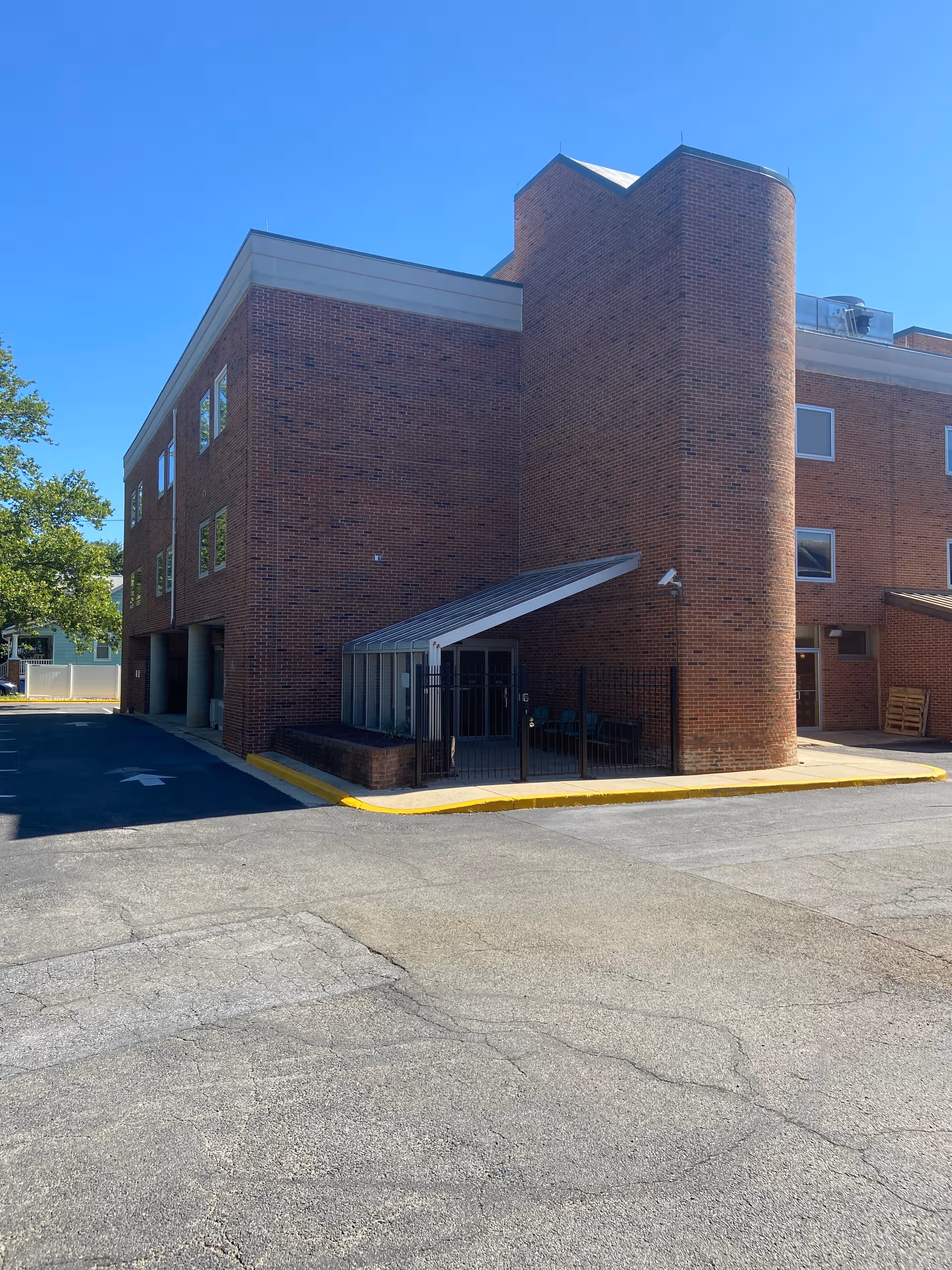 Brick senior living building exterior with glass entrance and curved tower.