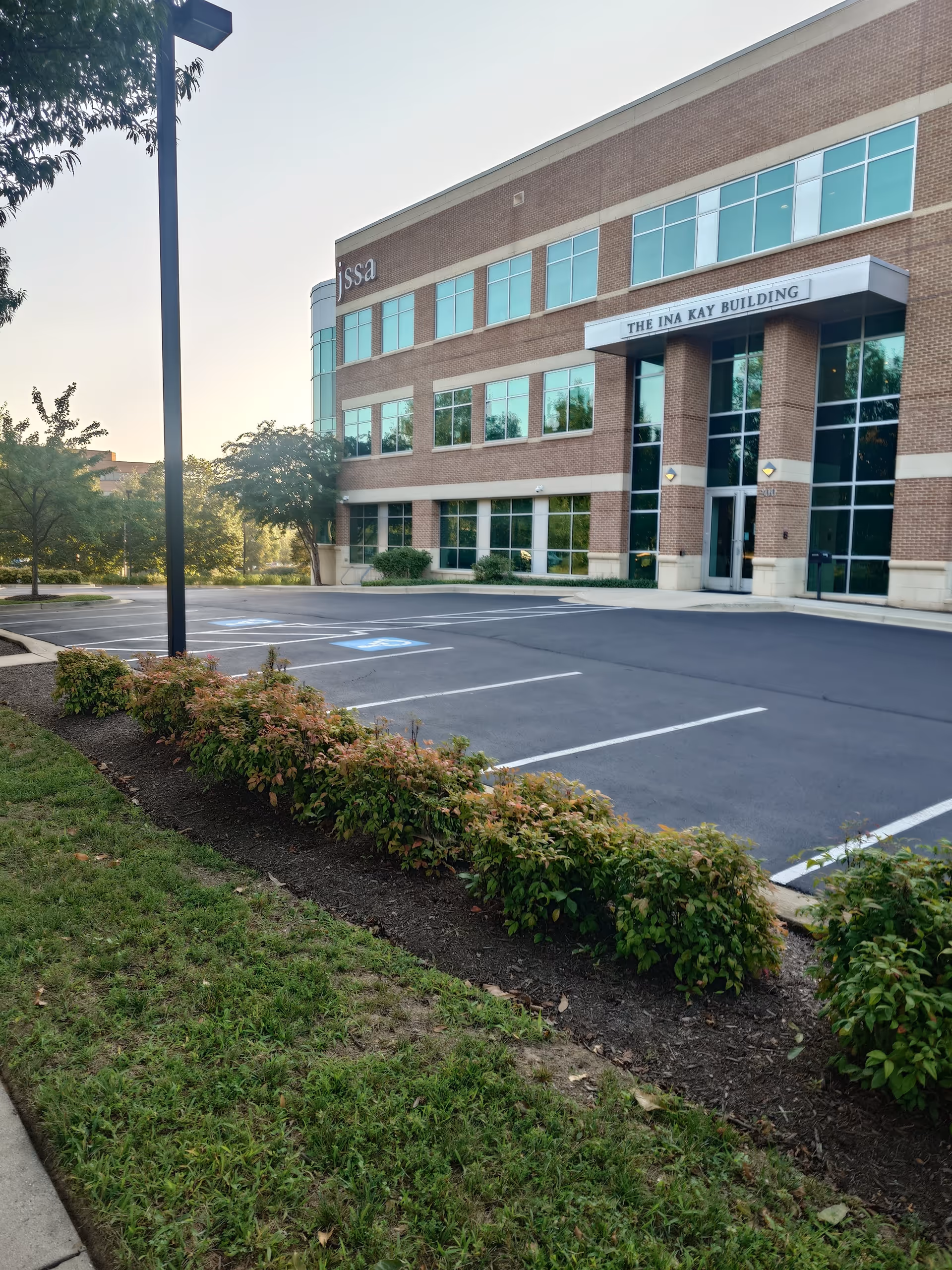 Exterior view of JSSA Ina Kay Building with brick facade, windows, and surrounding landscaping.