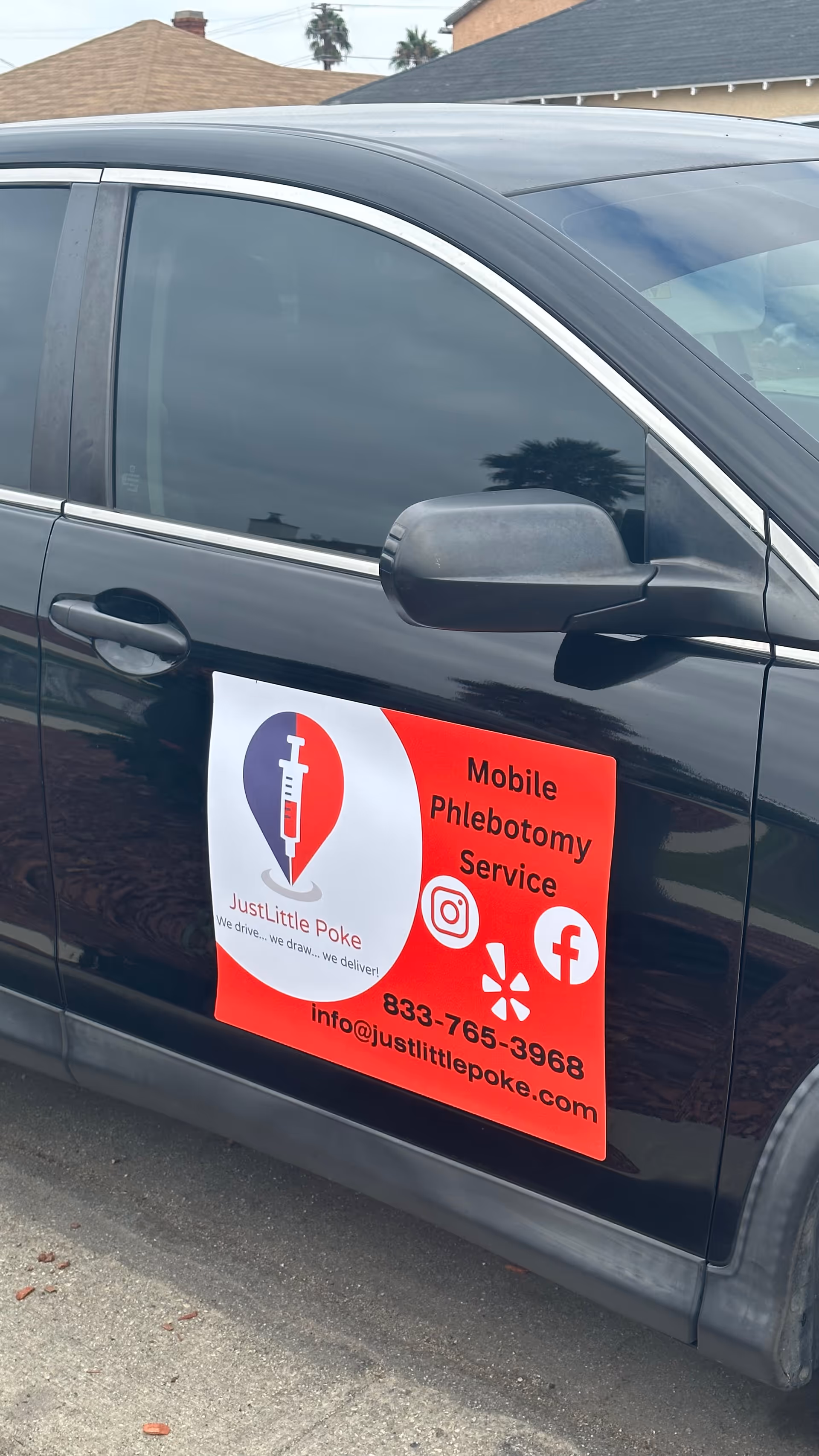 Close-up of a dark car door with a red Just Little Poke mobile phlebotomy sign.