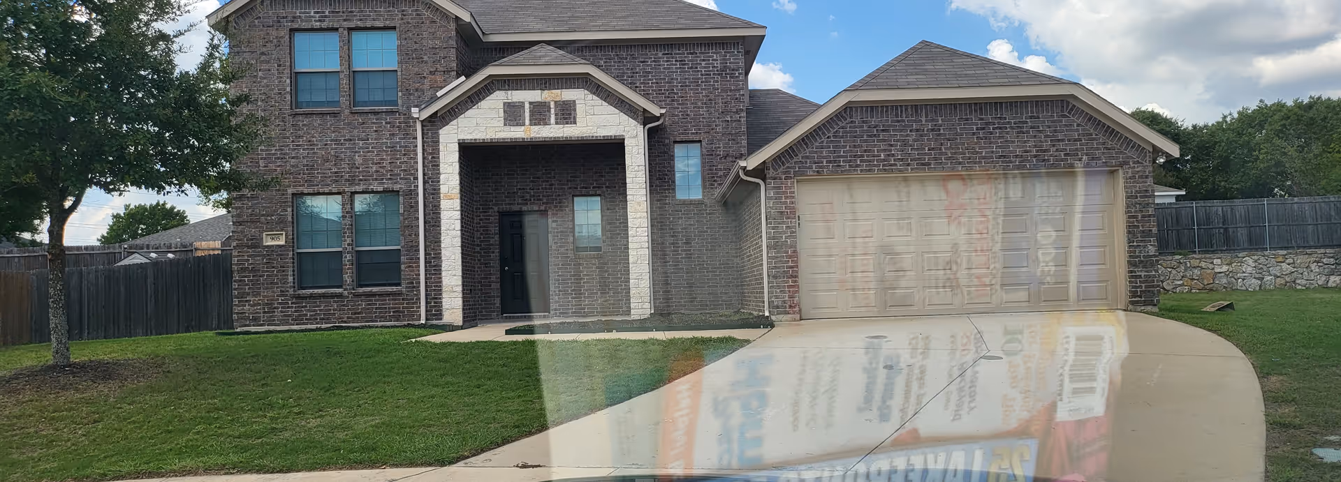 Brick two-story senior living facility front with curved driveway and double garage doors.