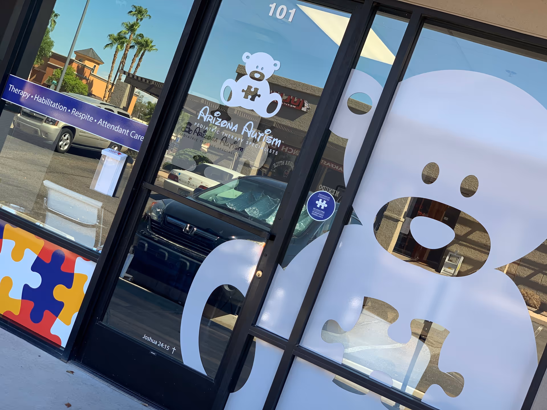 Storefront entrance with glass doors displaying Arizona Autism signage and a large bear graphic.