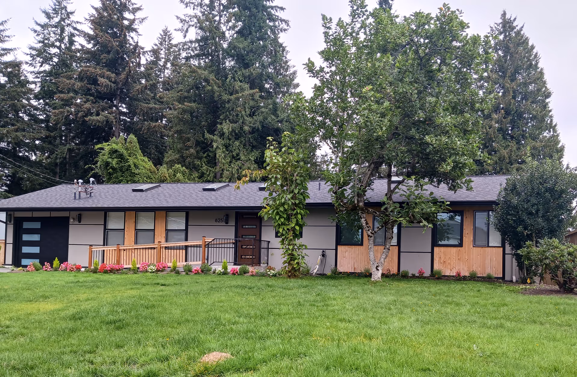 Front exterior of a single-story senior living home with lawn, trees, and wooden accent facade.